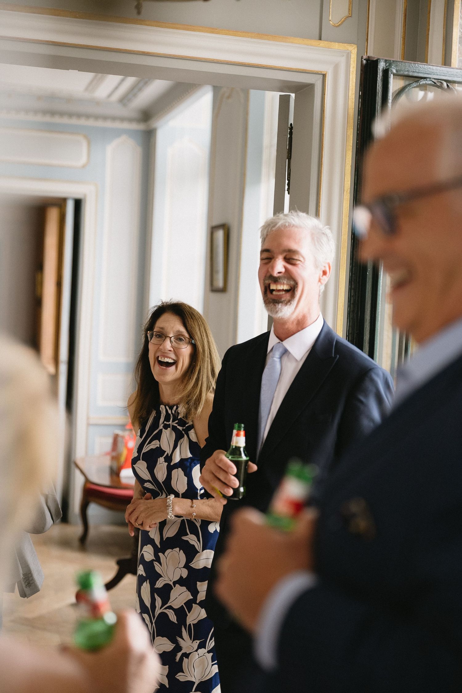 Candid shots of guests laughing and celebrating with drinks in an elegant indoor venue.