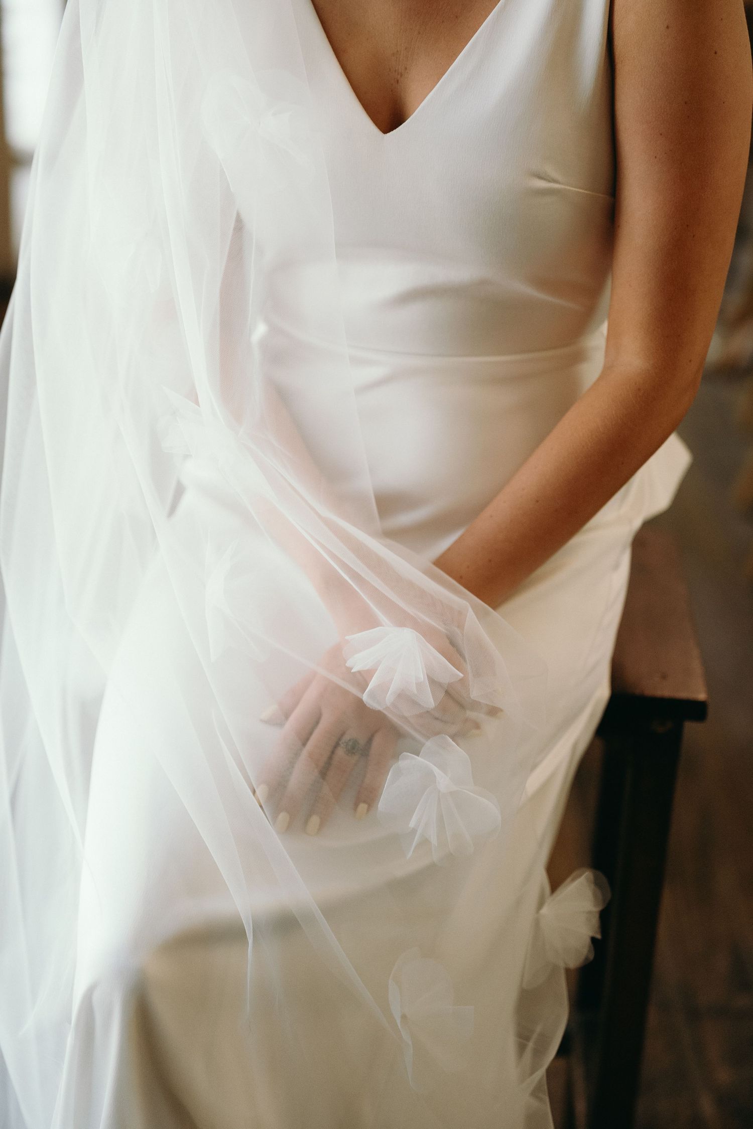 Close-up detail of white wedding dress with delicate veil overlay.