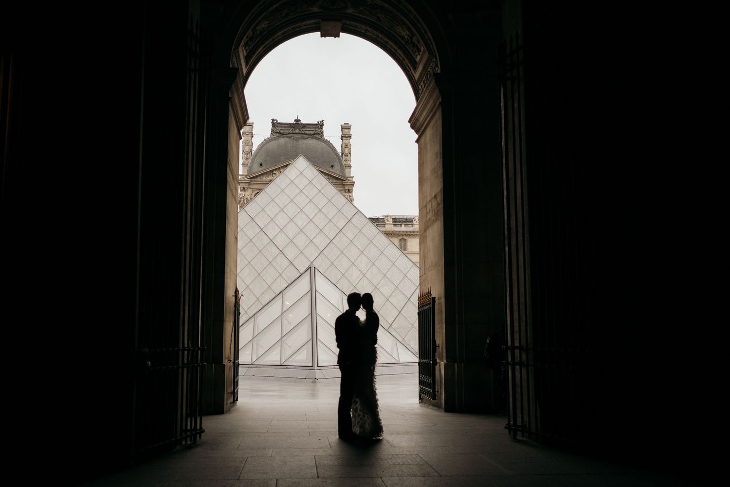 Silhouetted figures in an archway with dramatic lighting creating a romantic atmosphere.