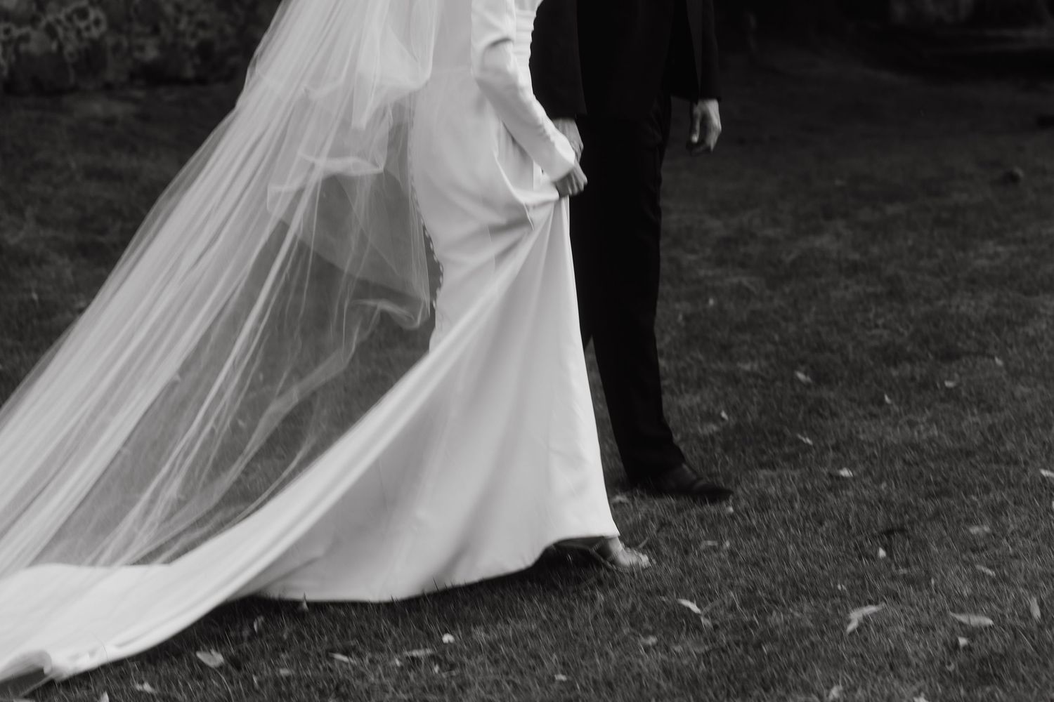Wedding dress flowing dramatically in the wind during an outdoor photoshoot.