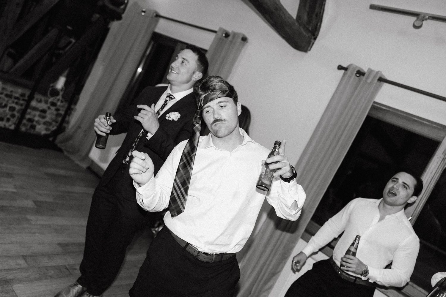 Wedding party guests dancing and celebrating with drinks in hand.
