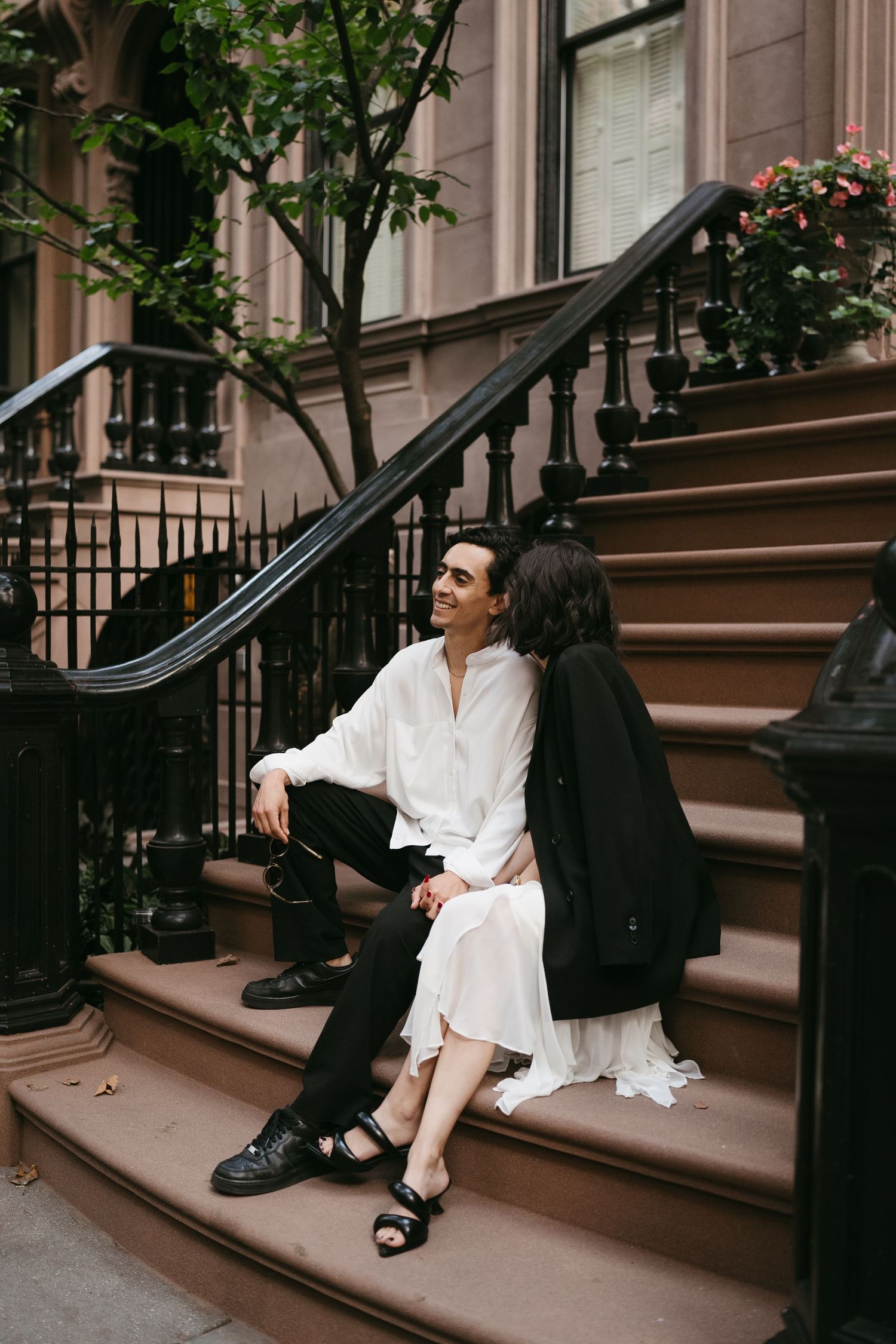 Couple sitting on brownstone steps in an urban setting.