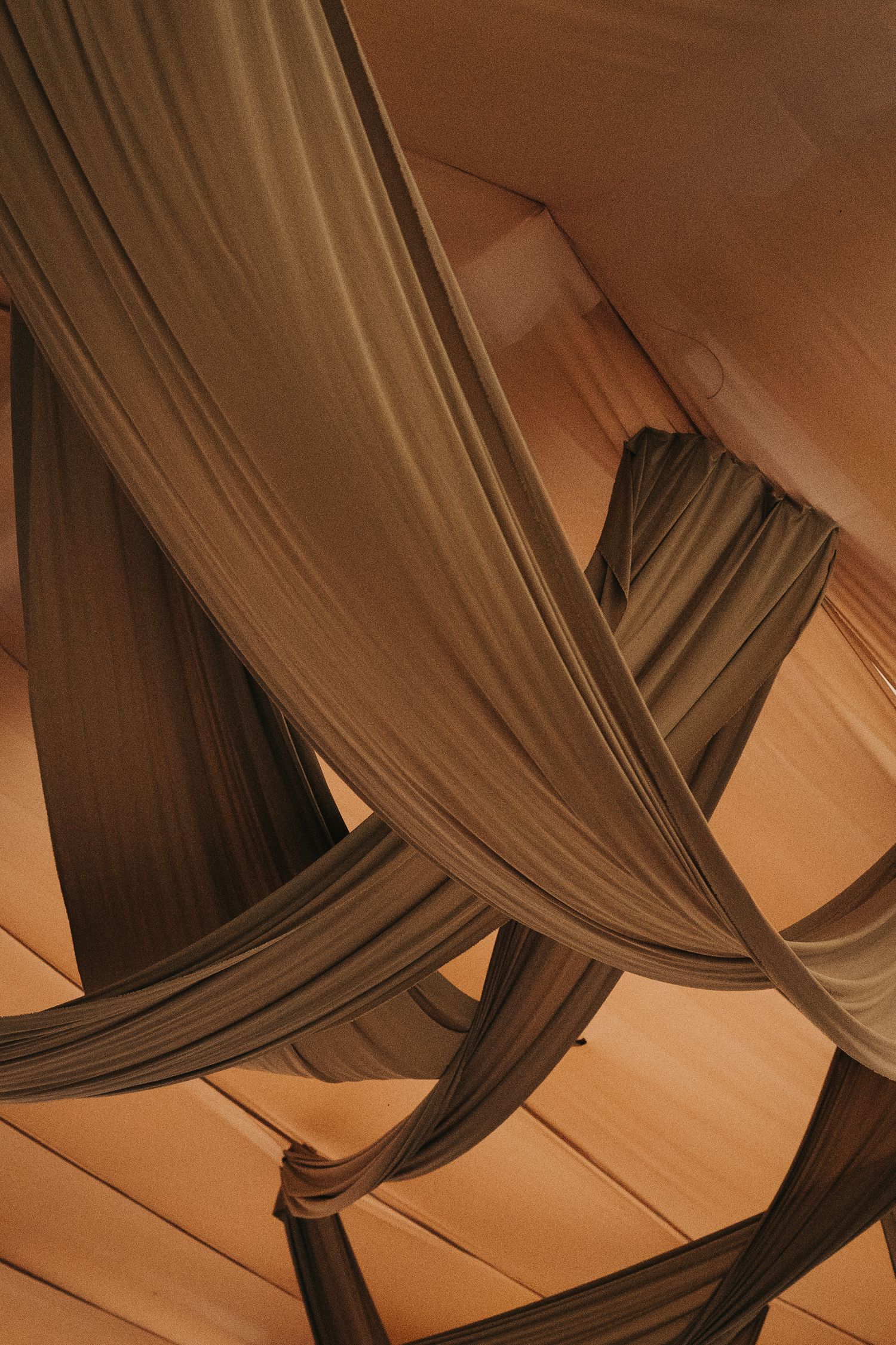 Abstract pattern of draped fabric in warm brown tones creating flowing lines.