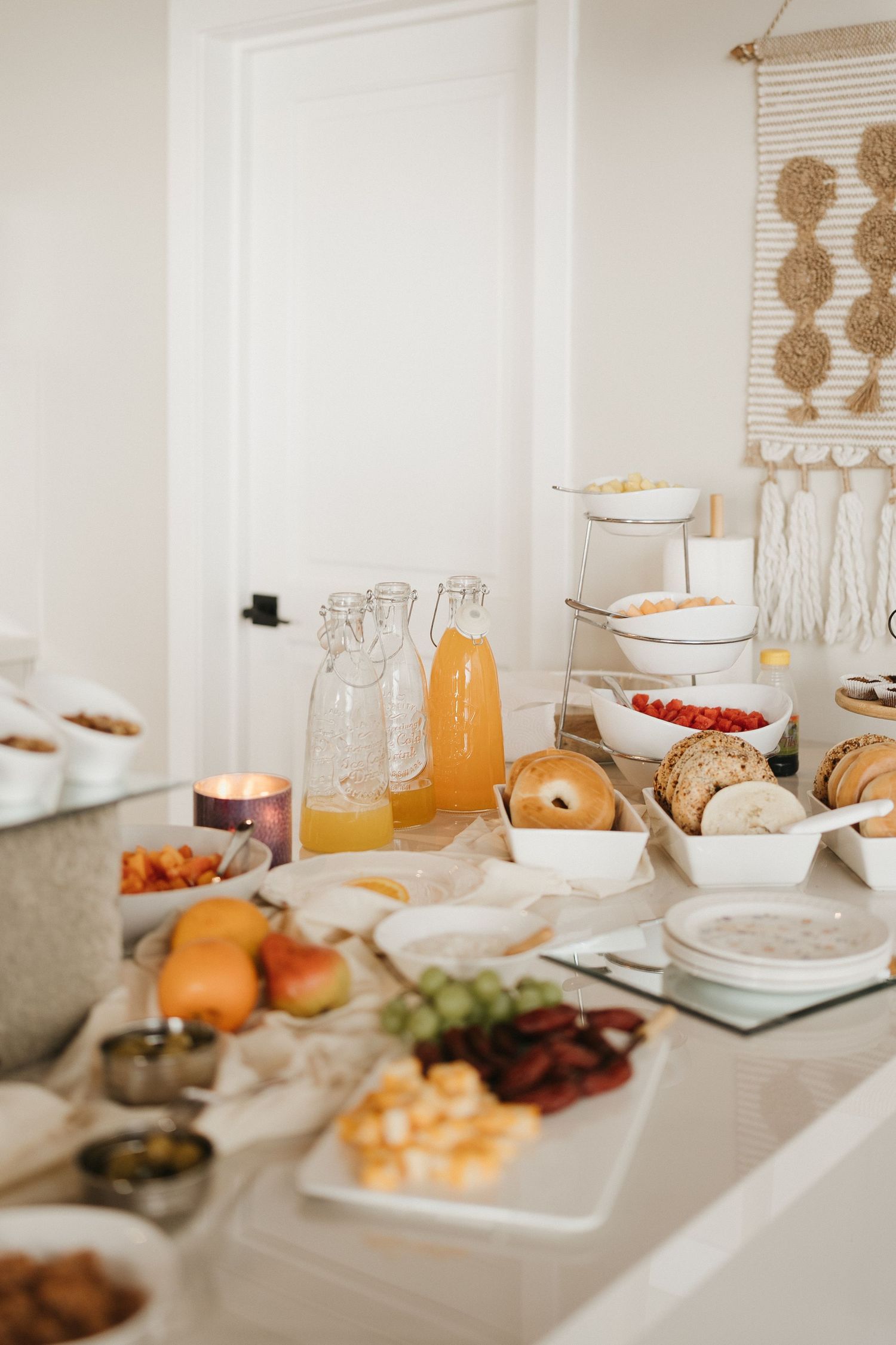 Elegant brunch setup with orange juice, pastries and breakfast items on a white table.