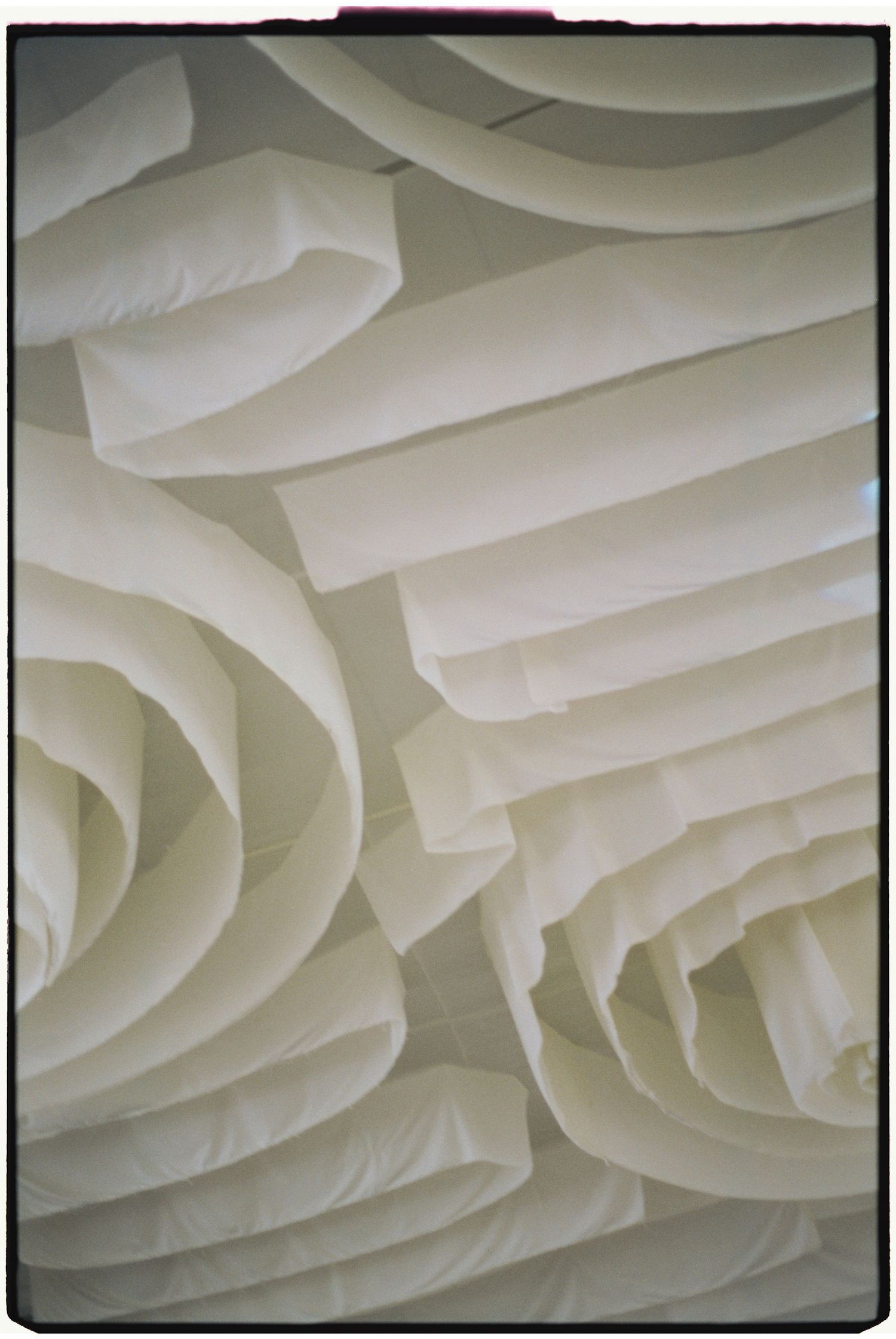 Abstract white fabric ceiling draping creates soft geometric patterns.