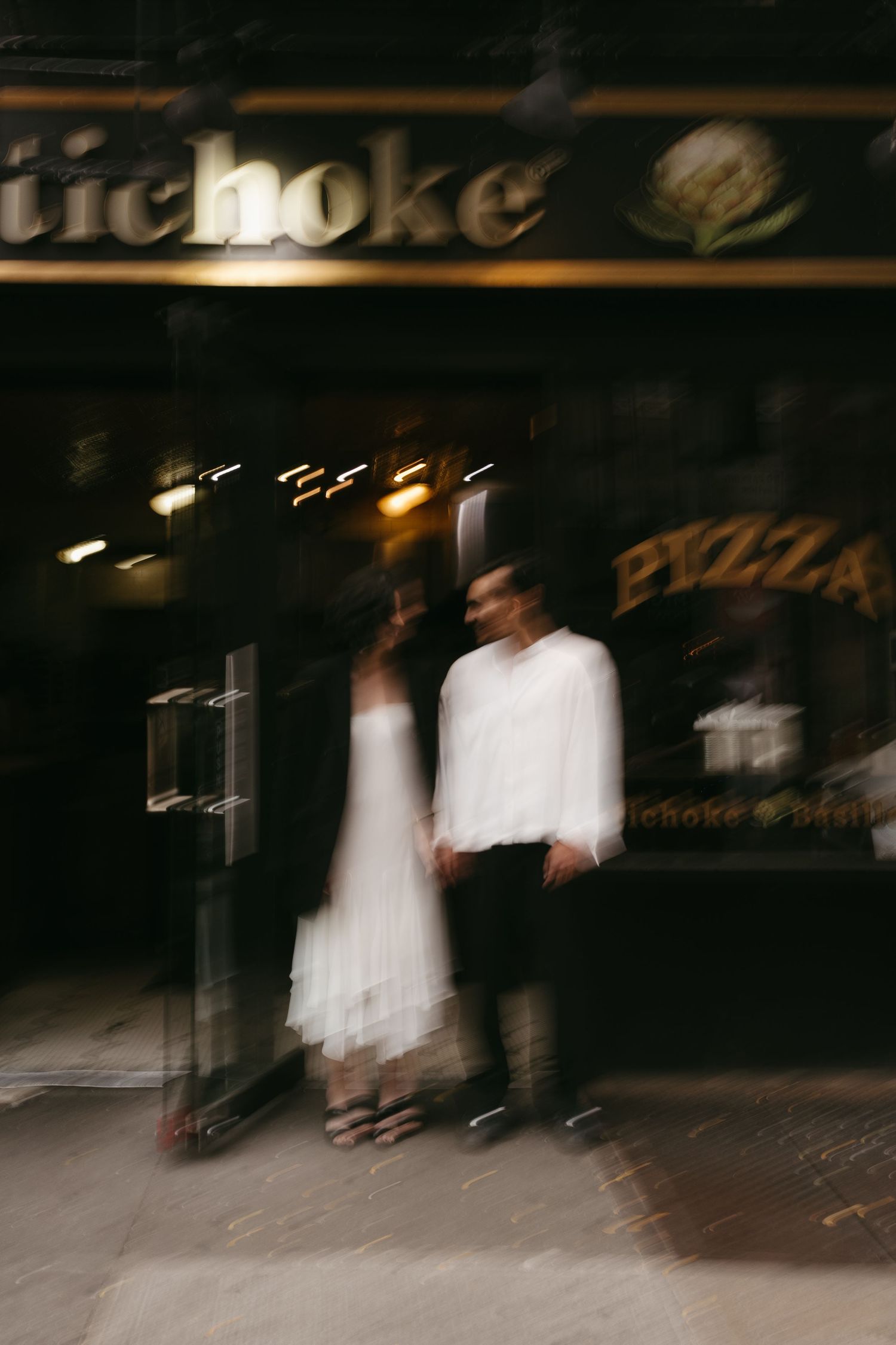 Blurred motion photo outside a pizza shop at night.