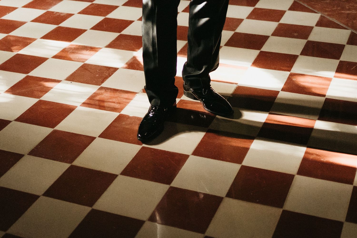 Black and white photo of feet on a checkered floor with dramatic lighting.