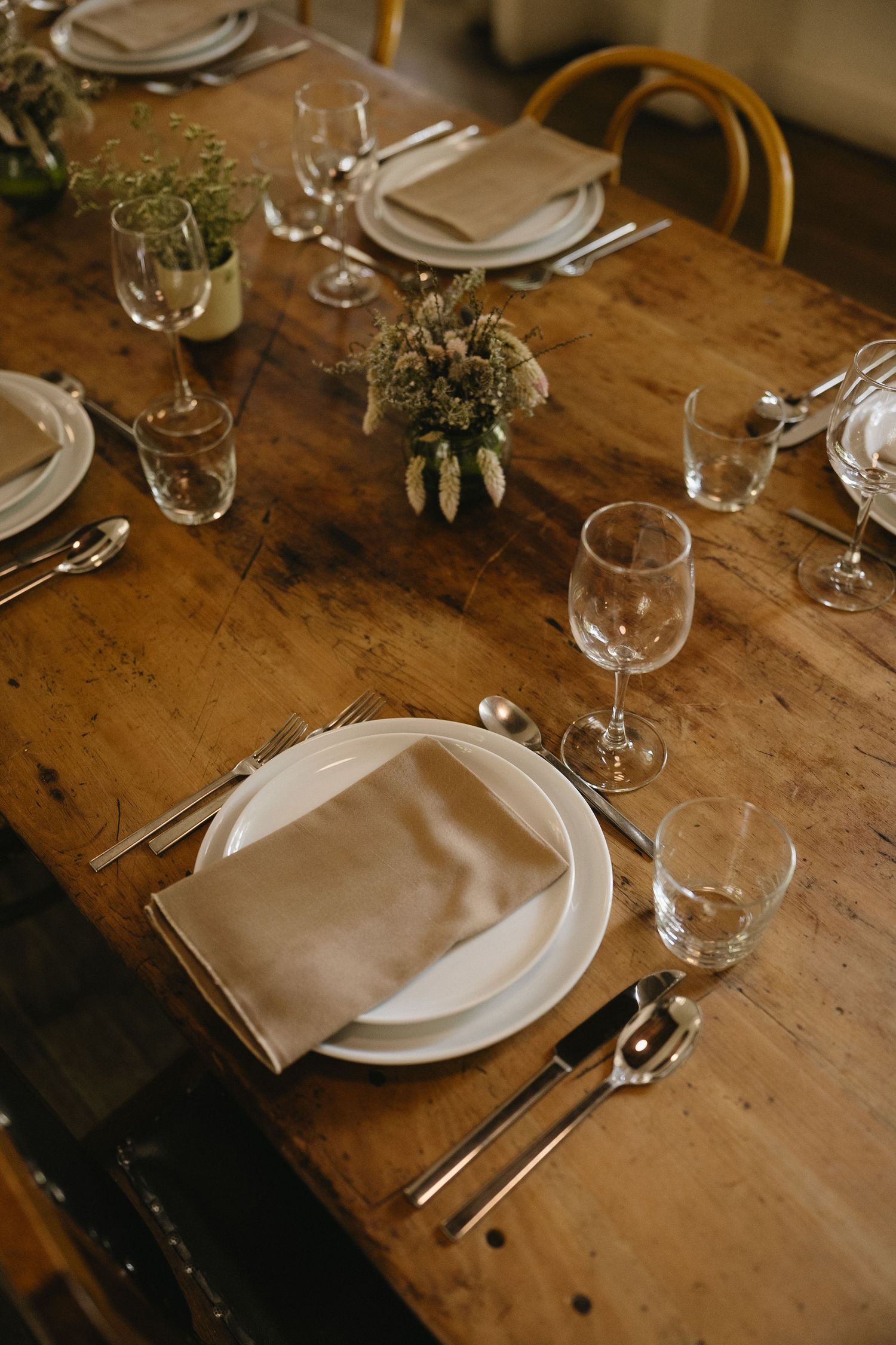 Rustic wooden table with elegant place settings and delicate floral arrangements.