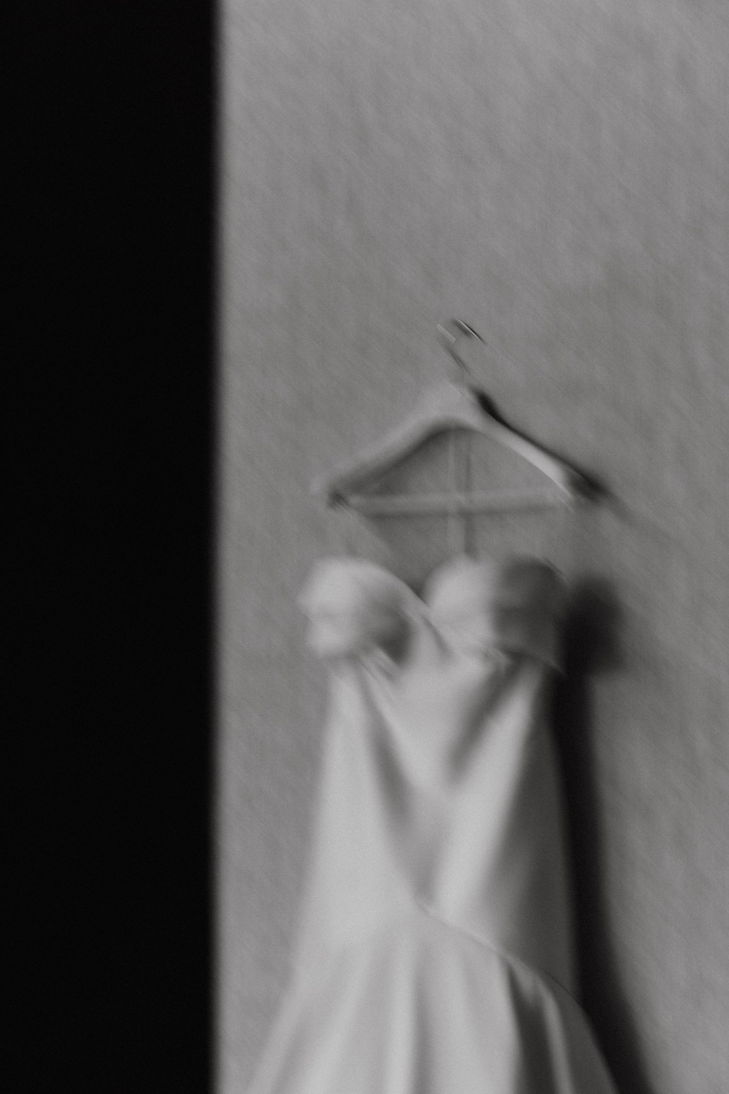 Artistic series showing a white wedding dress hanging against a textured wall.