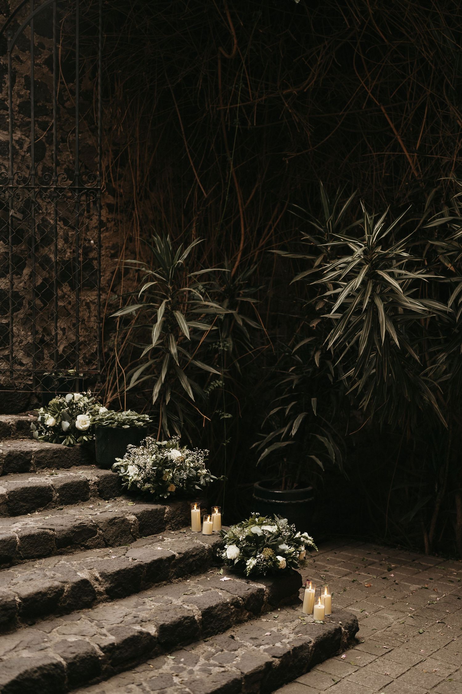 Candlelit stone steps decorated with tropical plants and white floral arrangements create an ambient atmosphere.