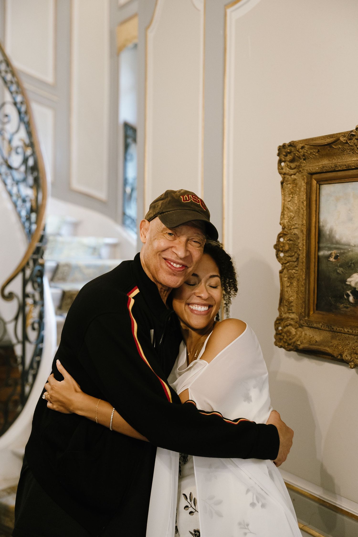 Candid moments of warm embraces and laughter in an elegant indoor setting with framed artwork.
