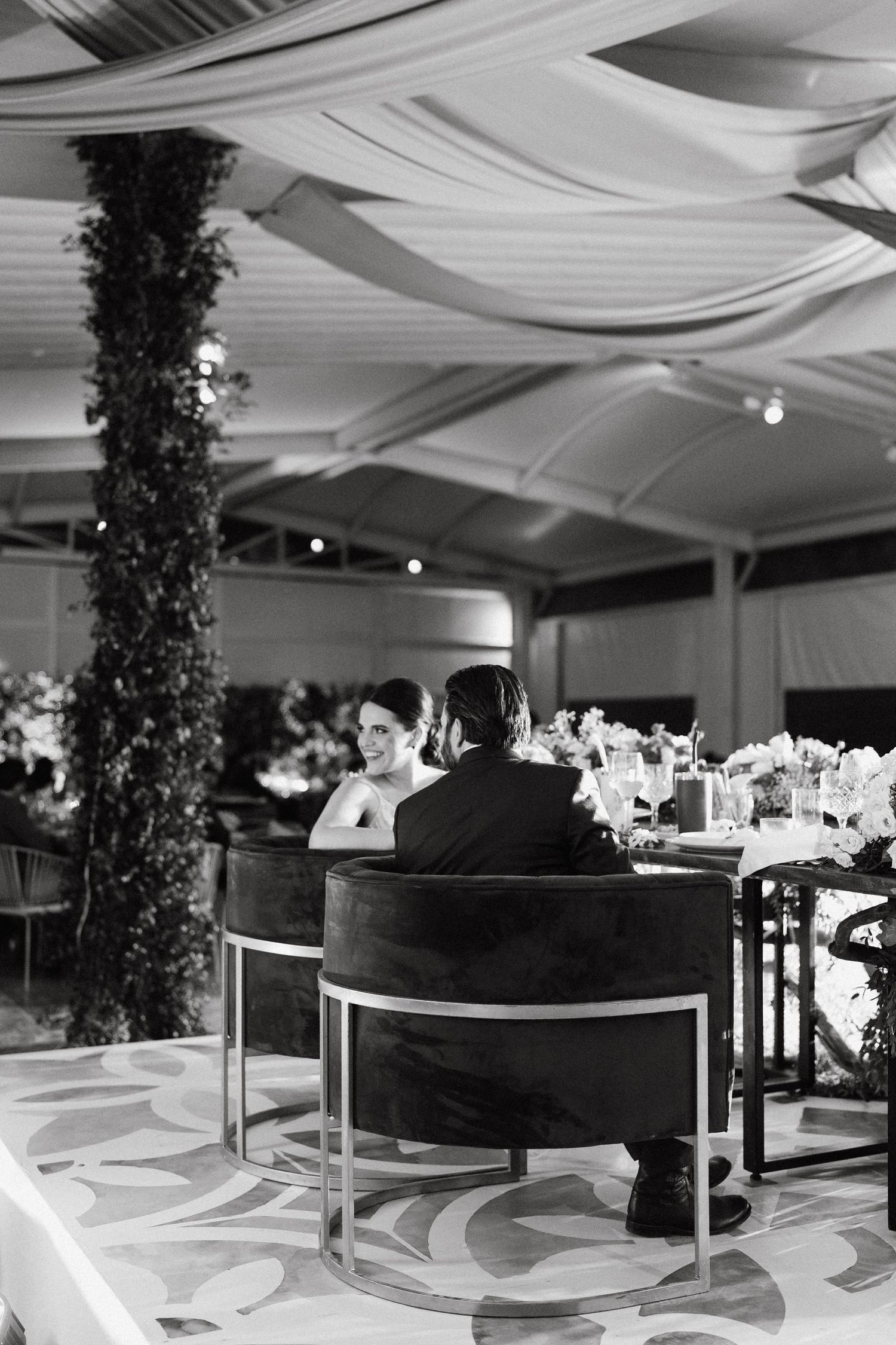 Wedding reception hall with elegant draping and floral decor in black and white.
