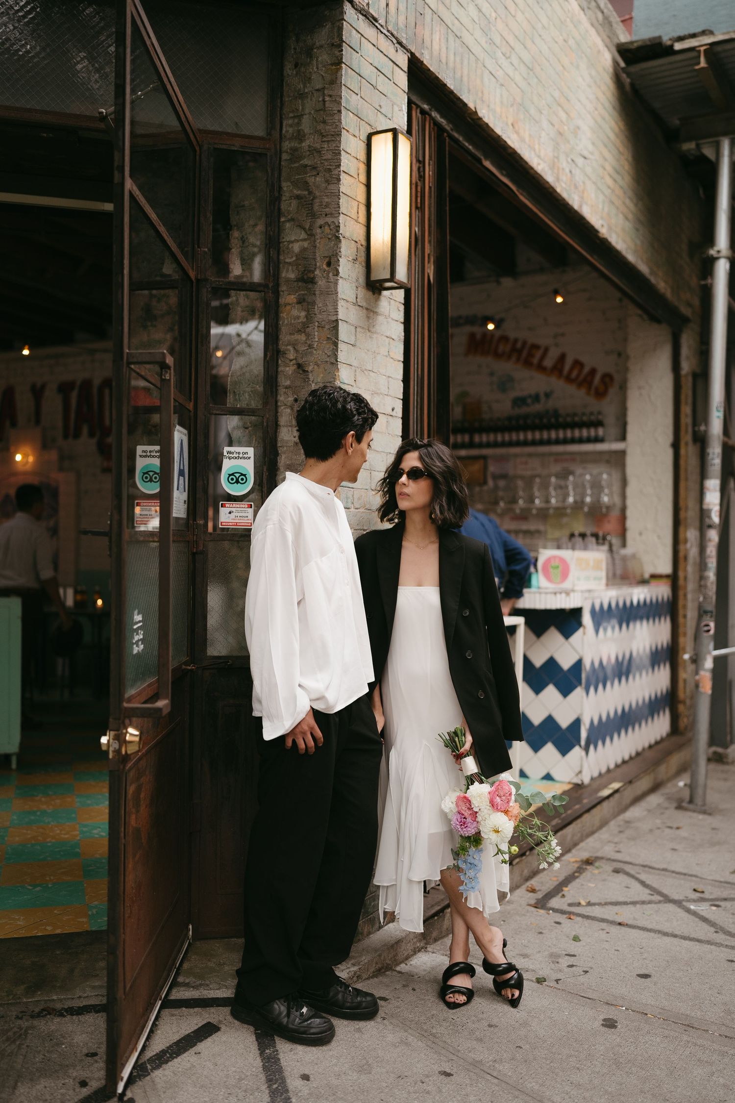 Two people stand outside a brick building with a chevron pattern wall design.