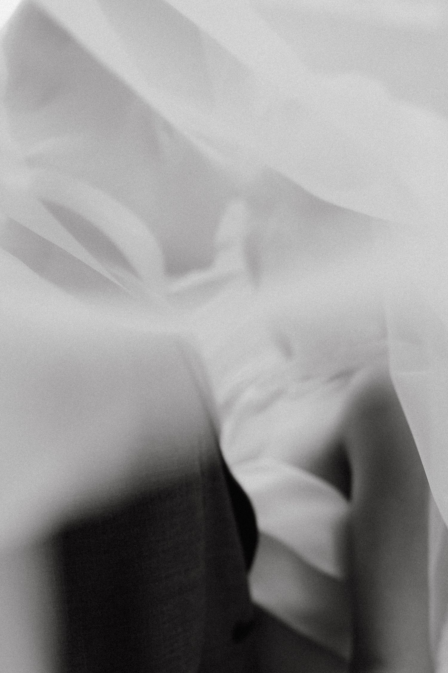 Abstract black and white close-up photograph showing soft fabric folds and shadows.