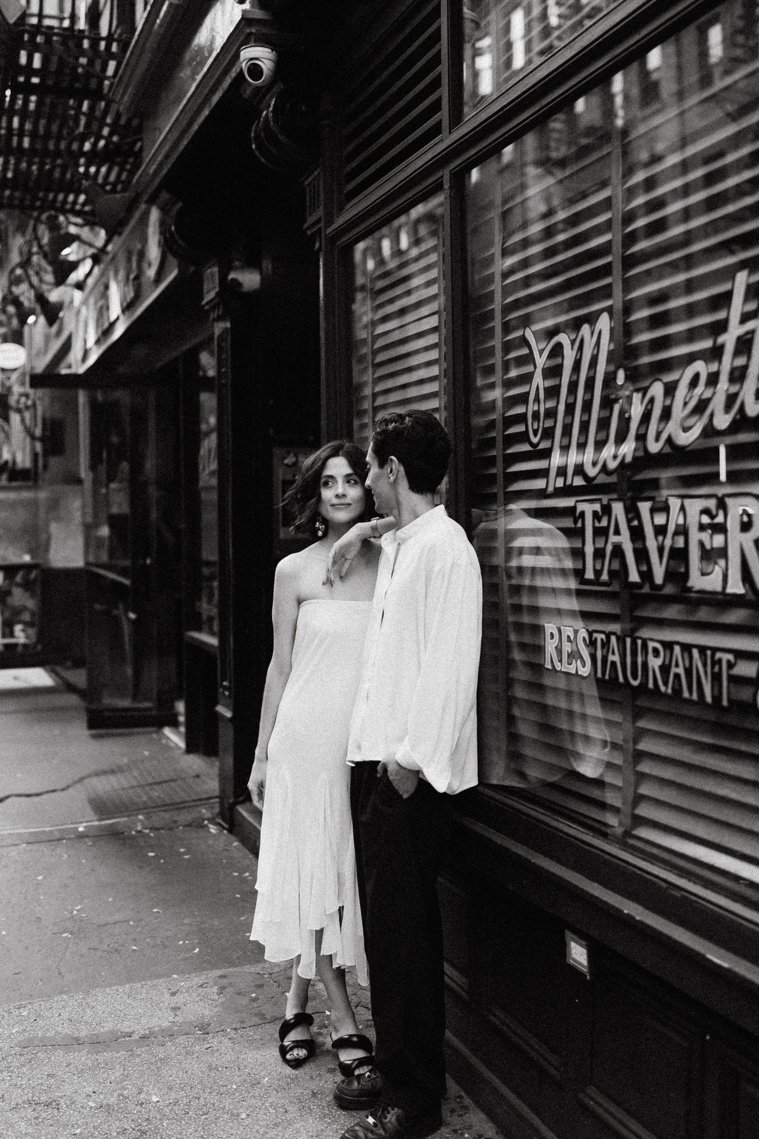 Two people standing outside a tavern restaurant with window signage.