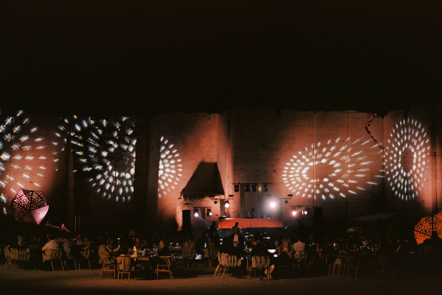 Outdoor nighttime light installation features illuminated geometric patterns and shapes projected across a dark space.