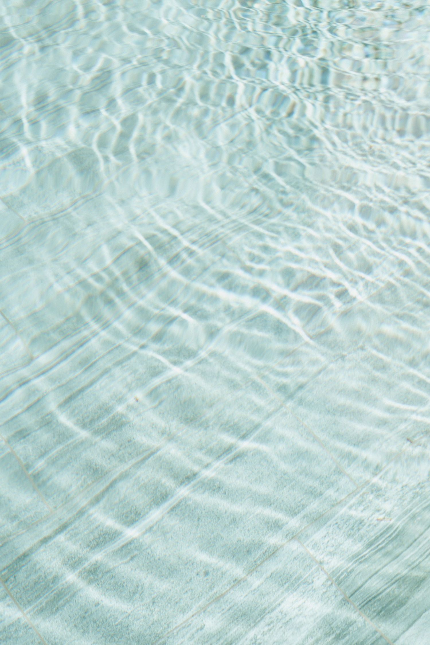 Rippling water surface creating abstract patterns in light turquoise tones.