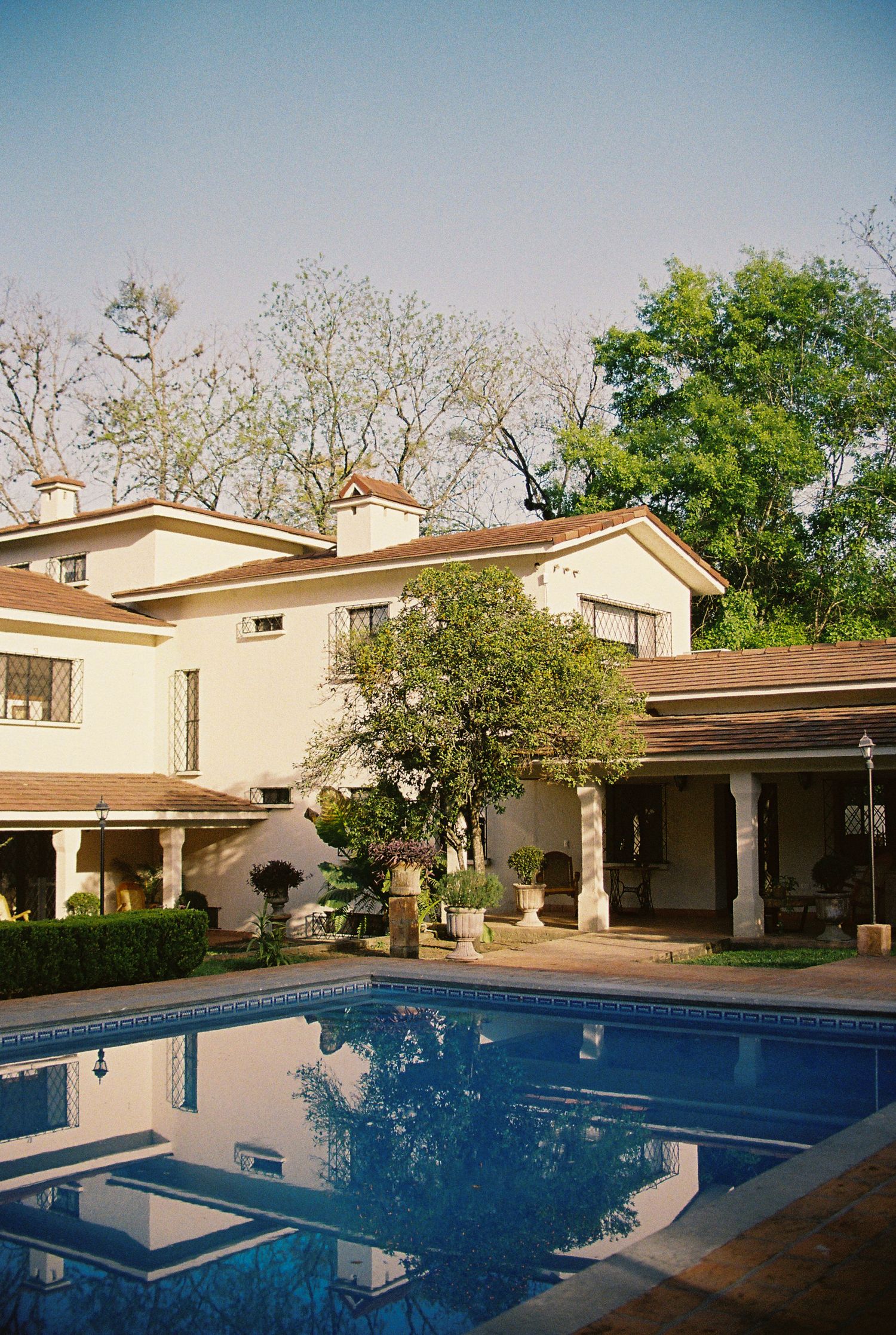 Modern luxury house exterior with swimming pool and landscaped yard on a sunny day.