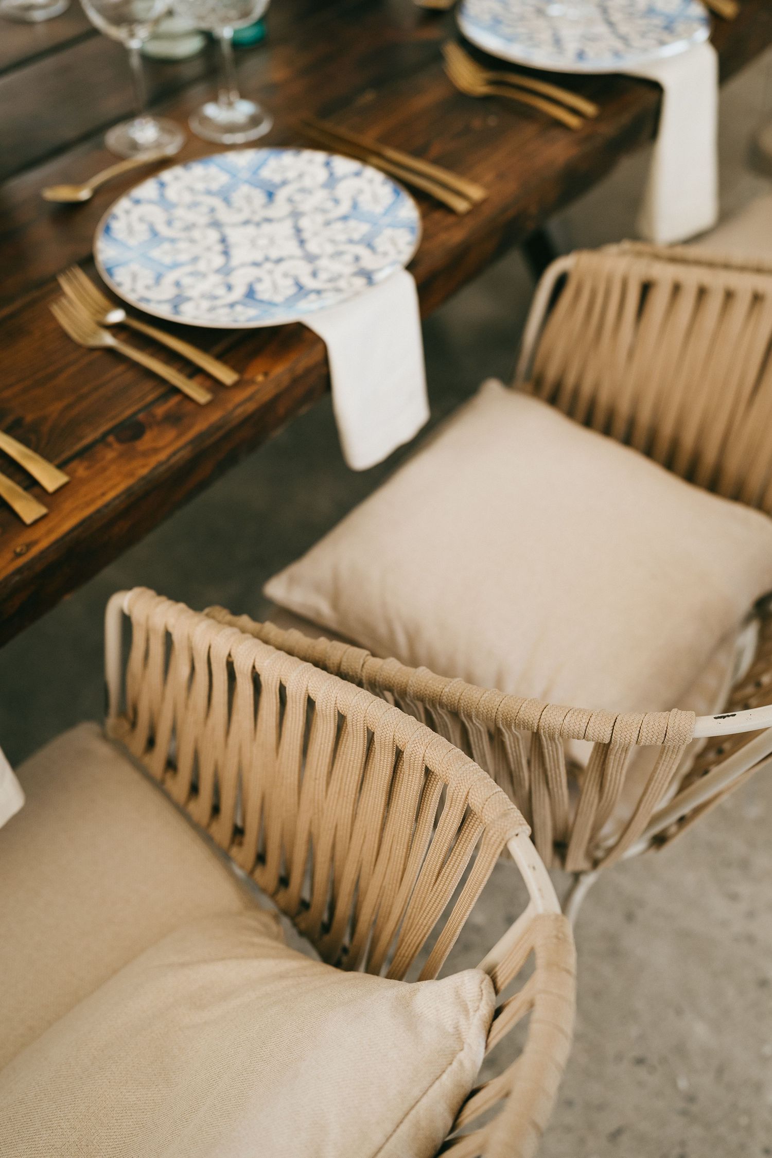 Rustic table setting with blue and white patterned plates and beige cushioned seating.