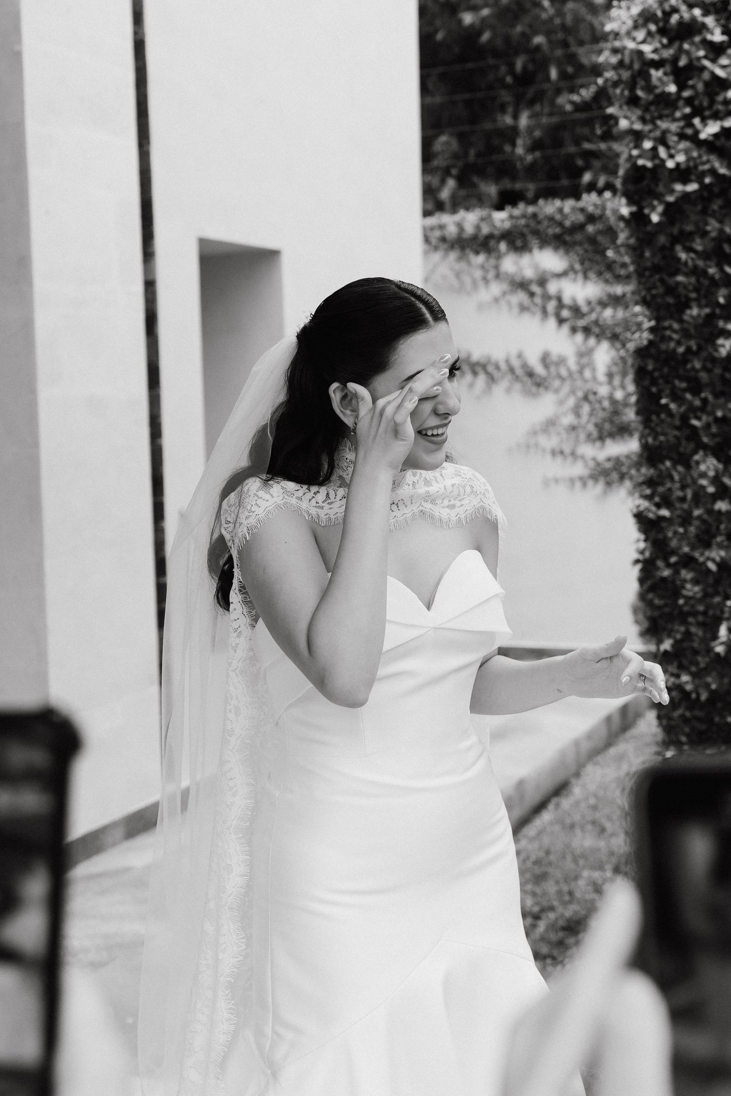 A bride in a white dress laughs joyfully during an outdoor photo session.