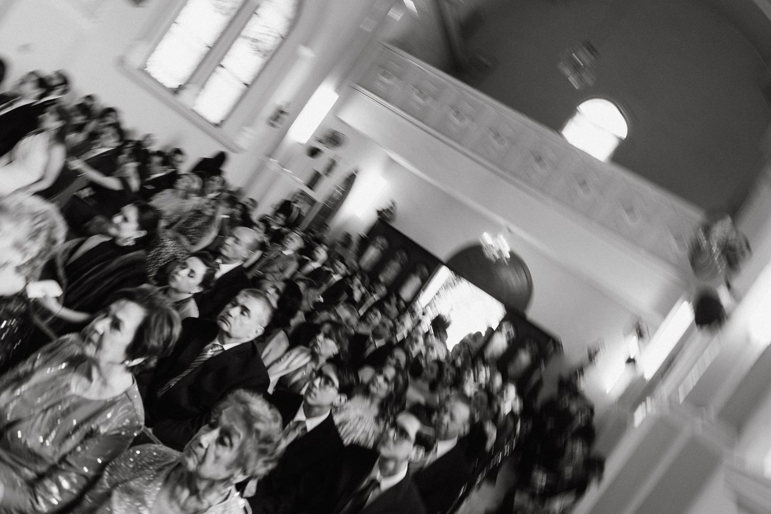 Wedding guests celebrating in a church hall with natural lighting.