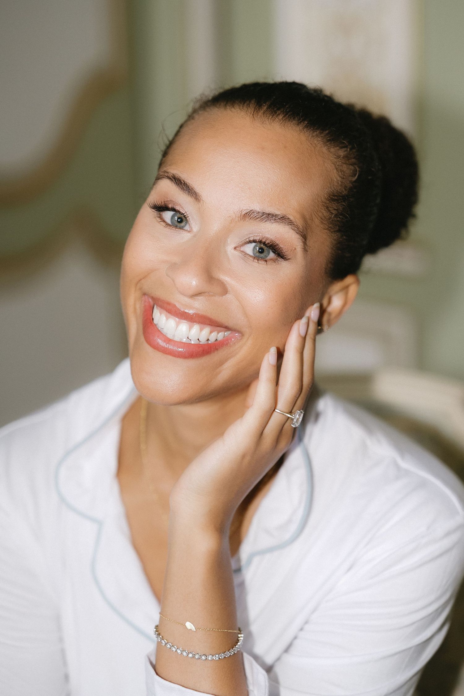 A radiant smile captured in a bridal getting-ready portrait with elegant jewelry and makeup.