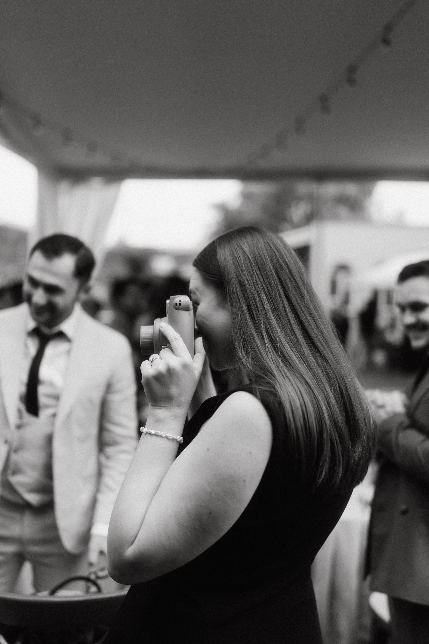 Black and white profile shot of wedding guests during an outdoor reception.