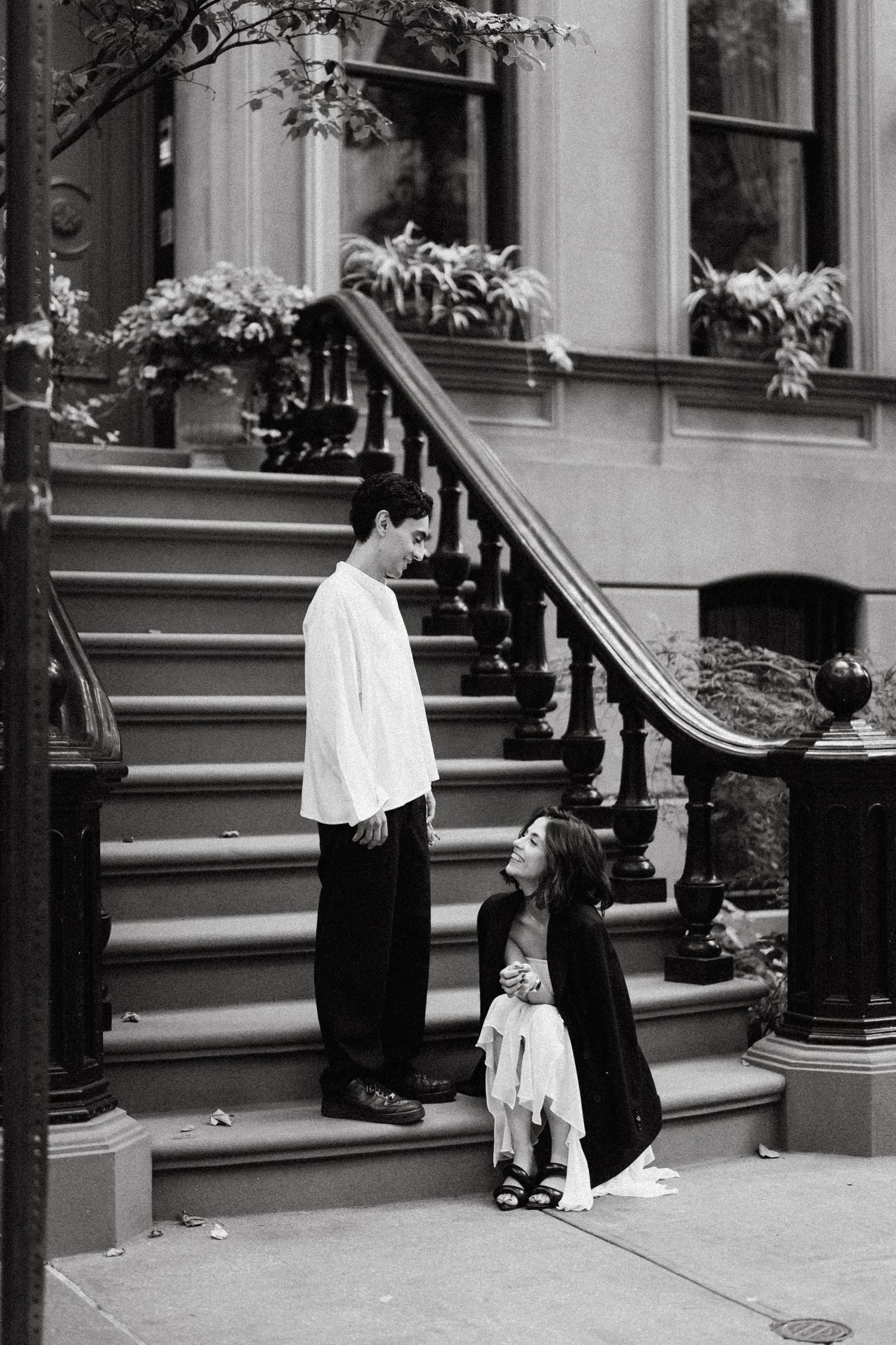 Black and white photo of people near brownstone building steps.