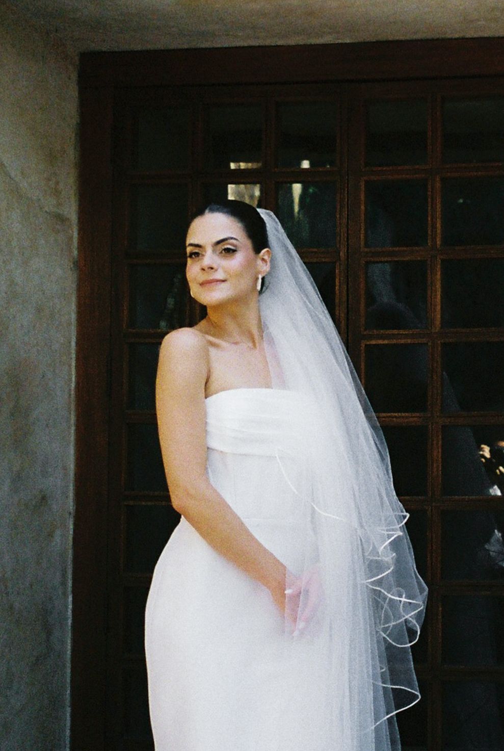 Elegant bridal portraits with flowing veil in classic architectural setting.