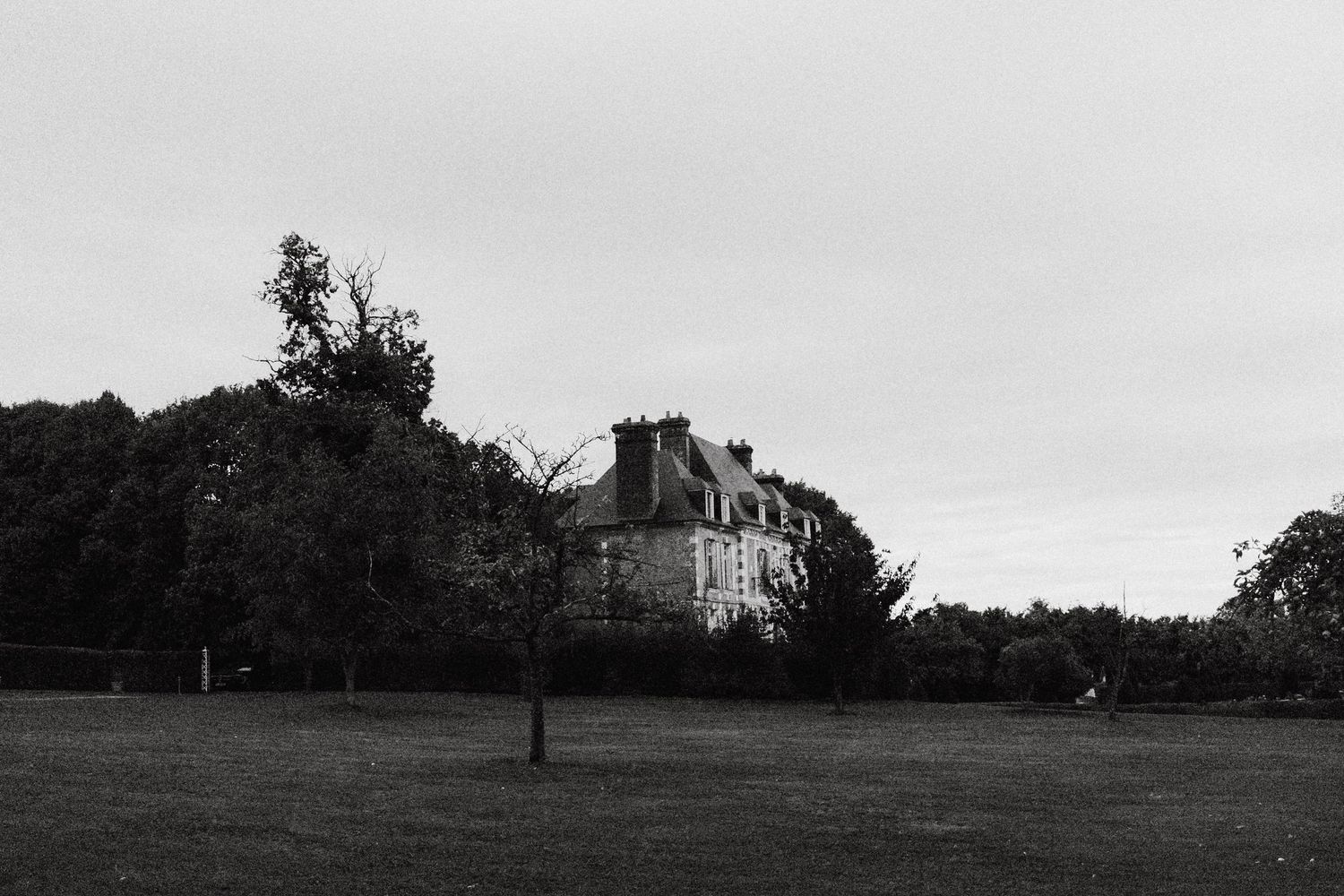 Black and white photograph of a grand chateau mansion with sprawling grounds.