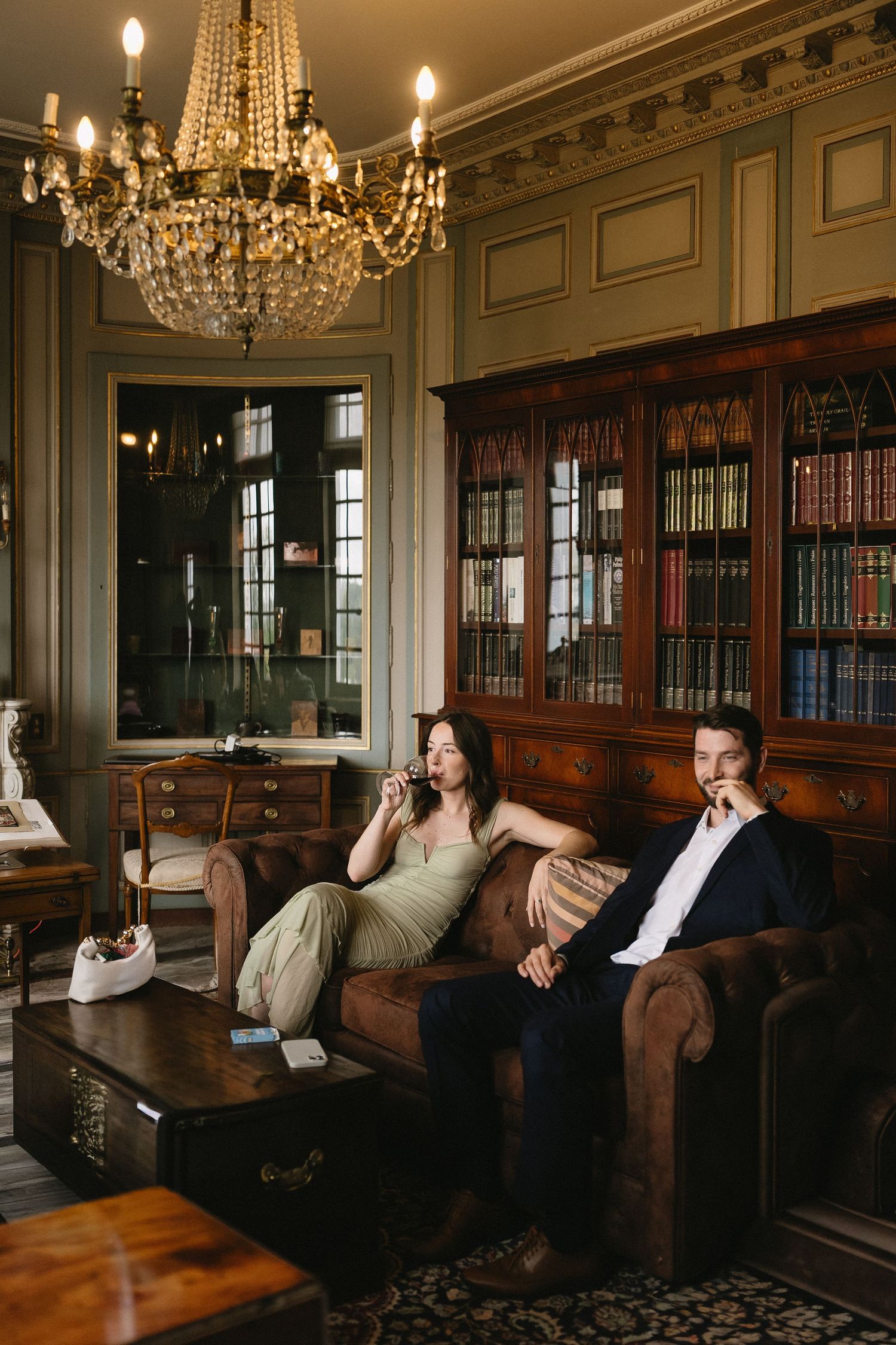 Elegant library interior with crystal chandeliers and leather couches showcases a classic study atmosphere.