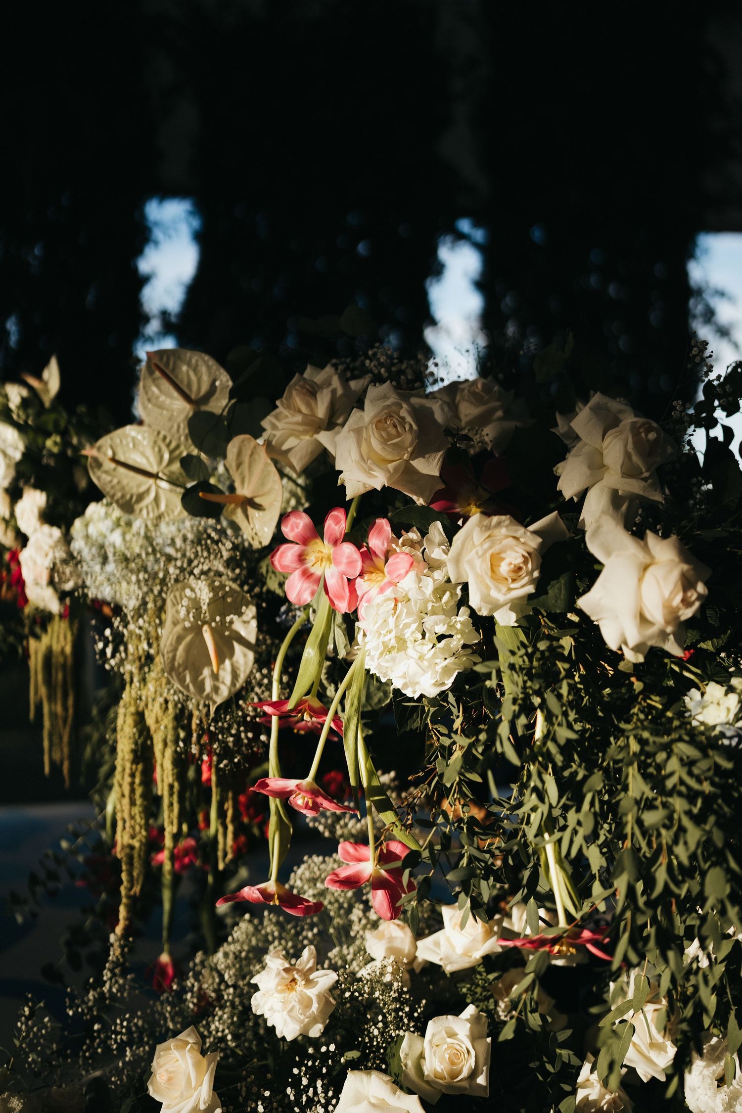 Romantic floral arrangement with white and pink roses against a dark background.