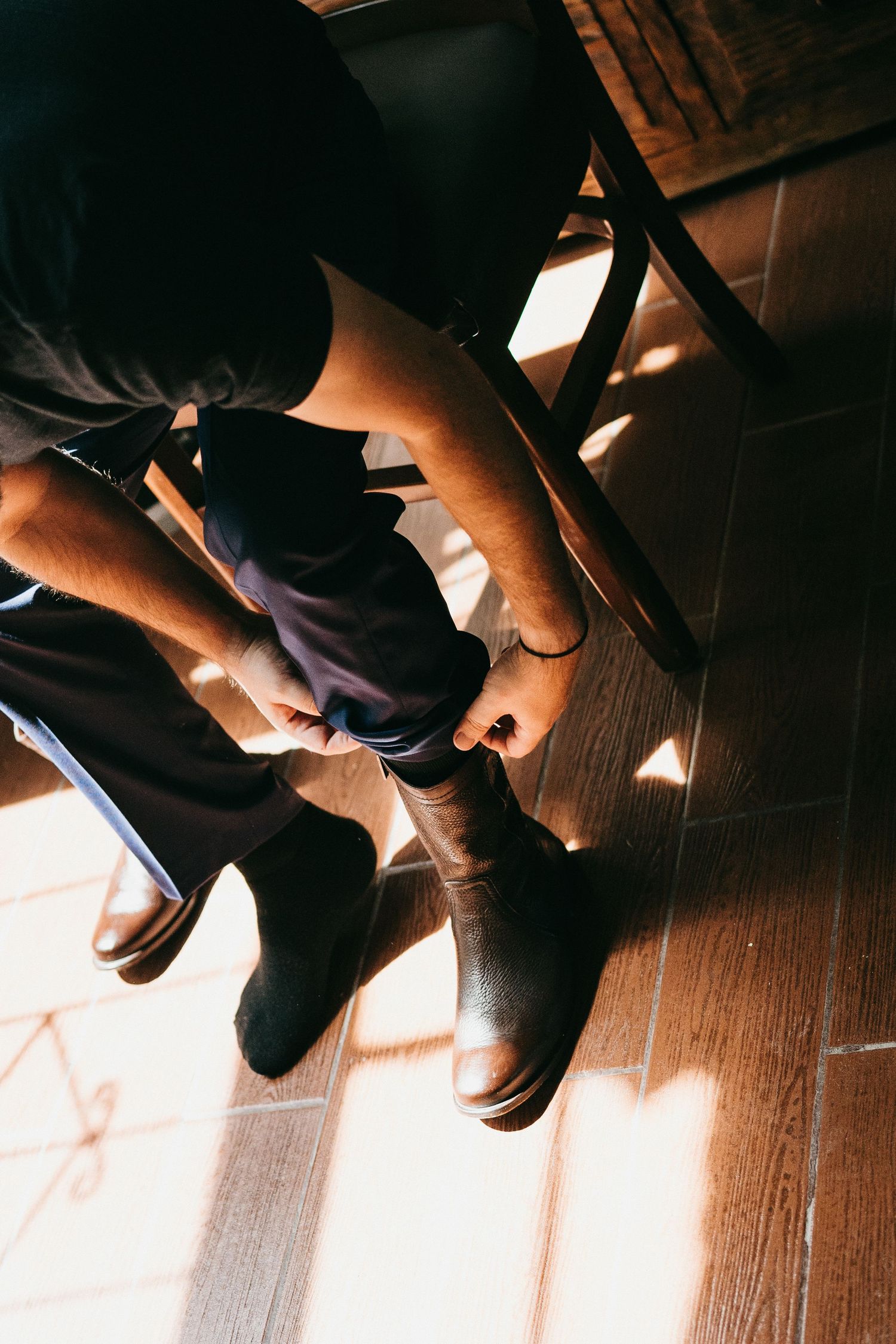 Detail shots of dress shoes and formal wear being put on in warm lighting.