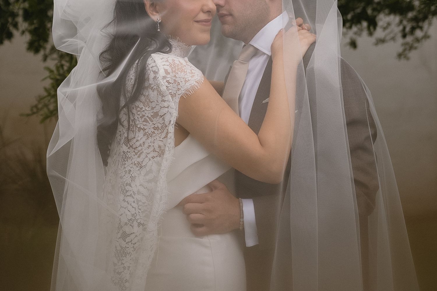 A romantic wedding moment captured in soft focus with flowing white veil details.