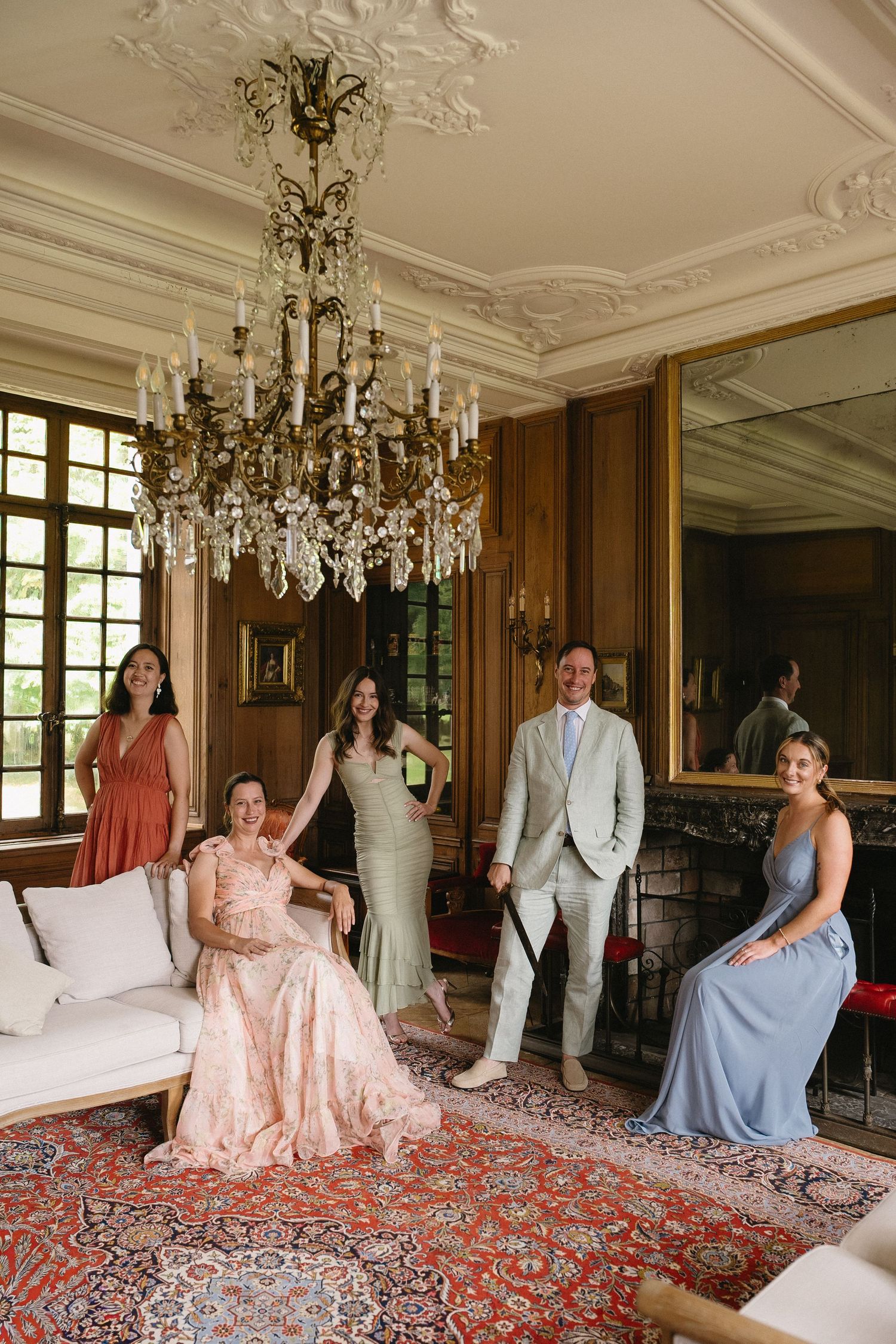 Elegant wedding party photos in a luxurious French chateau interior with crystal chandeliers.