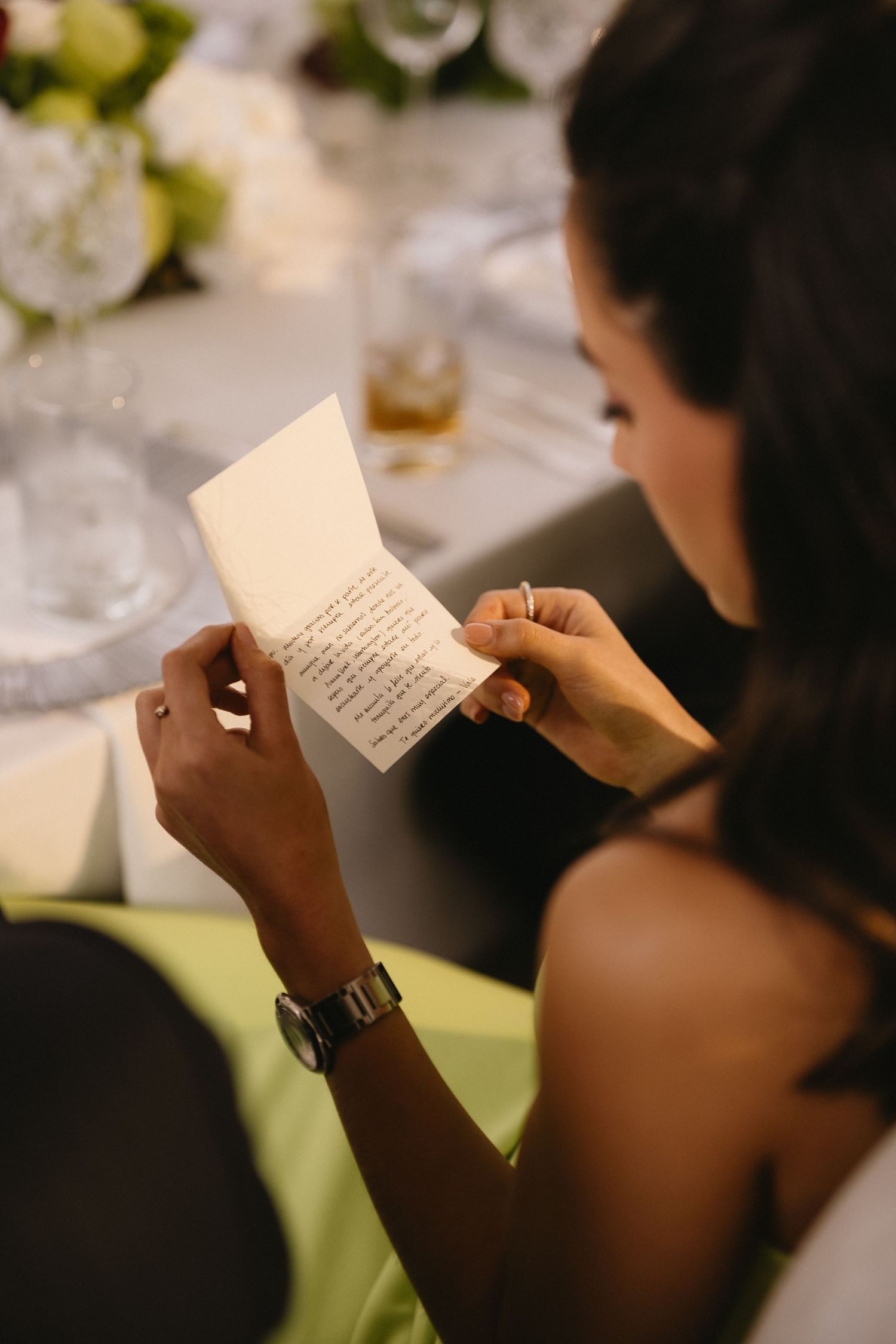 Guest reading a handwritten note at an elegant wedding reception.