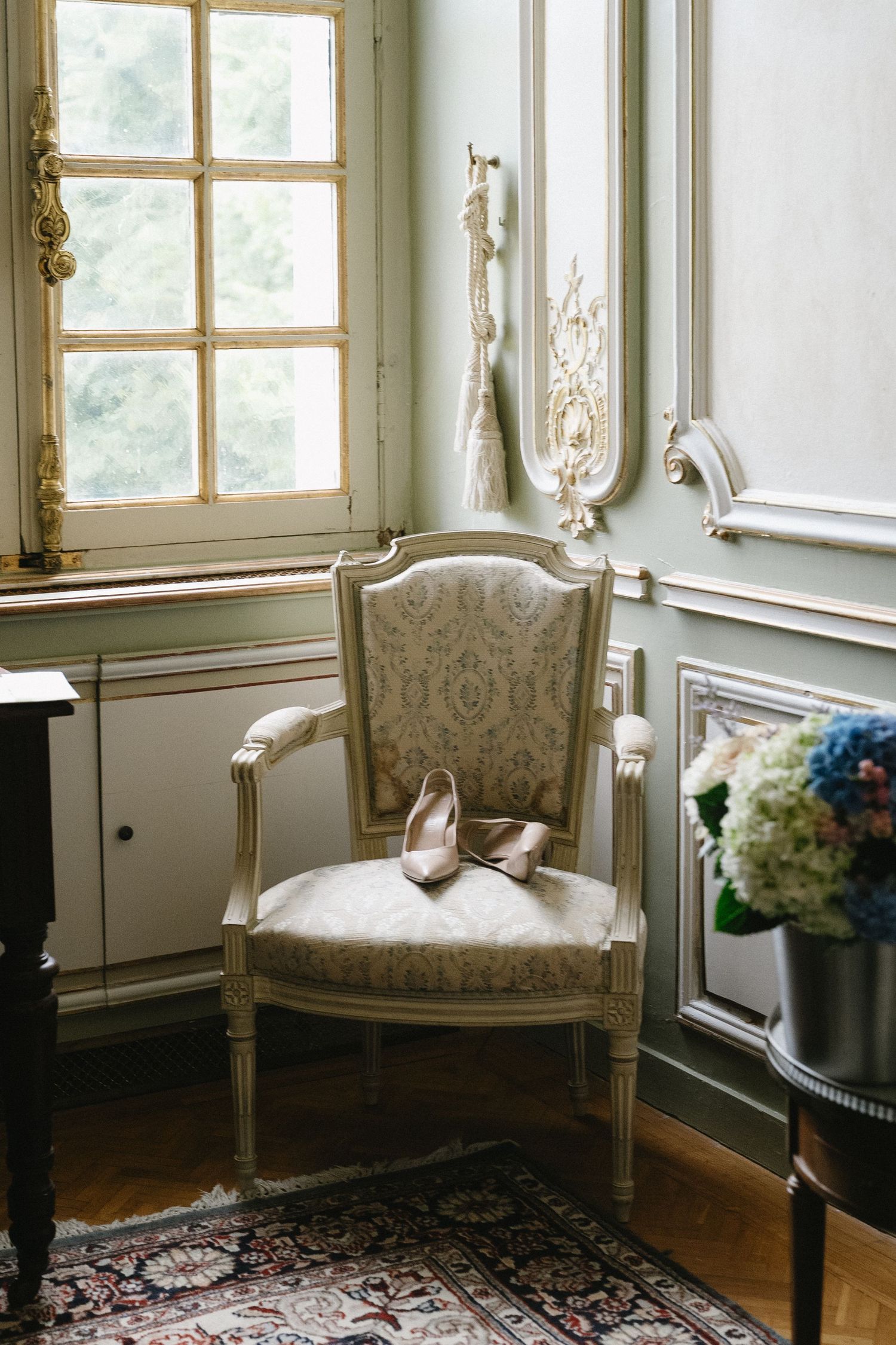 Elegant sitting room with antique furniture, large windows, and ornate wall details.