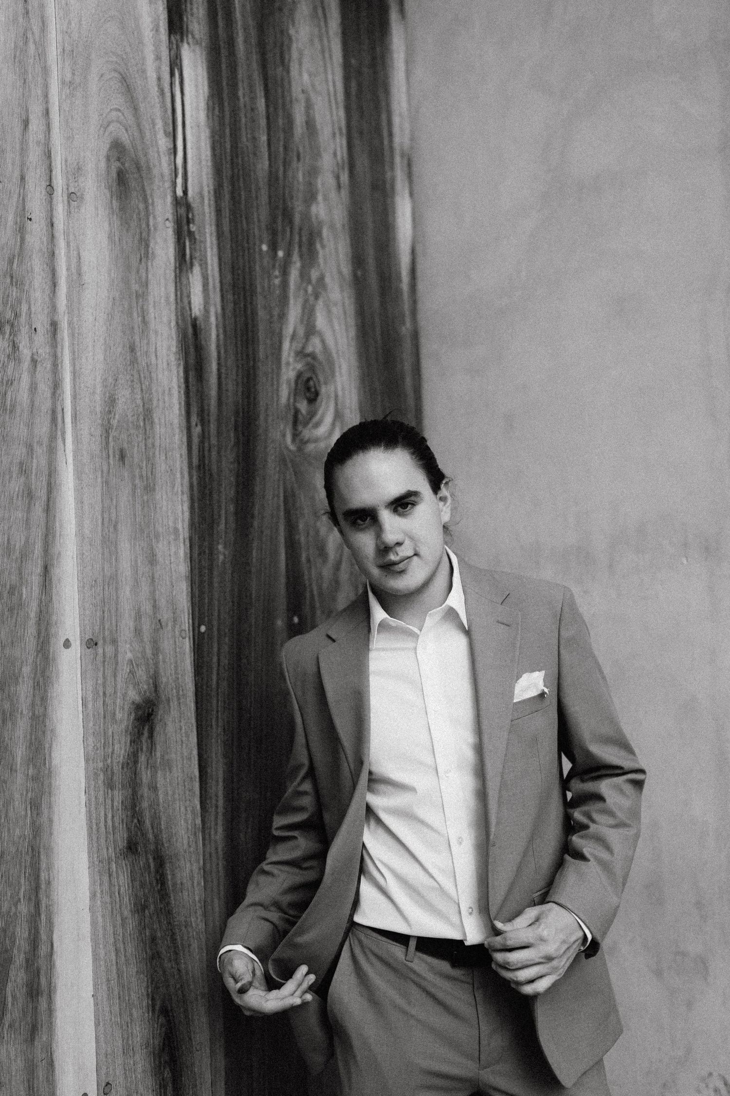 A sequence of black and white portraits showing a person in a suit against wooden panels.