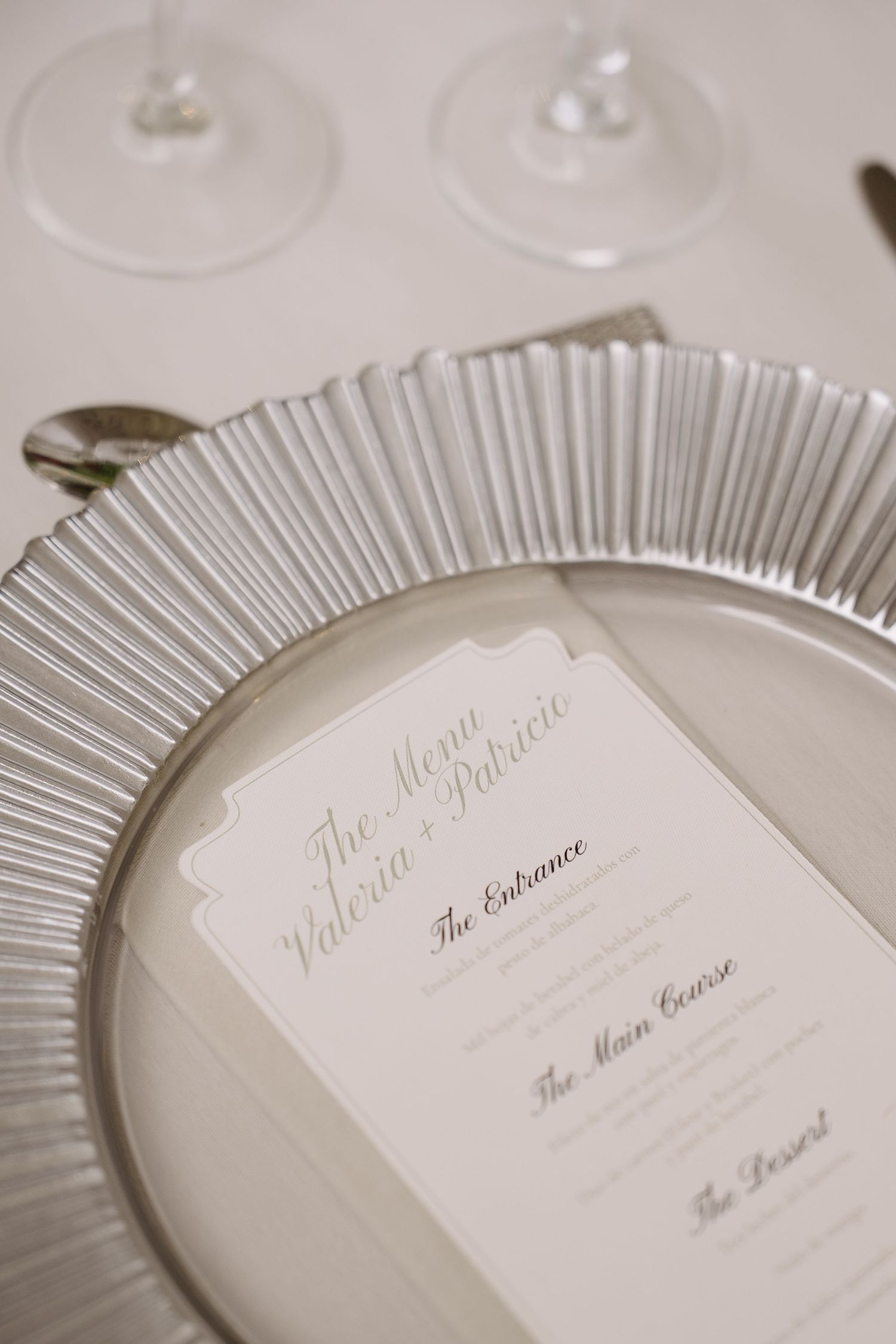 Elegant white menu card on silver-rimmed plate at formal place setting.