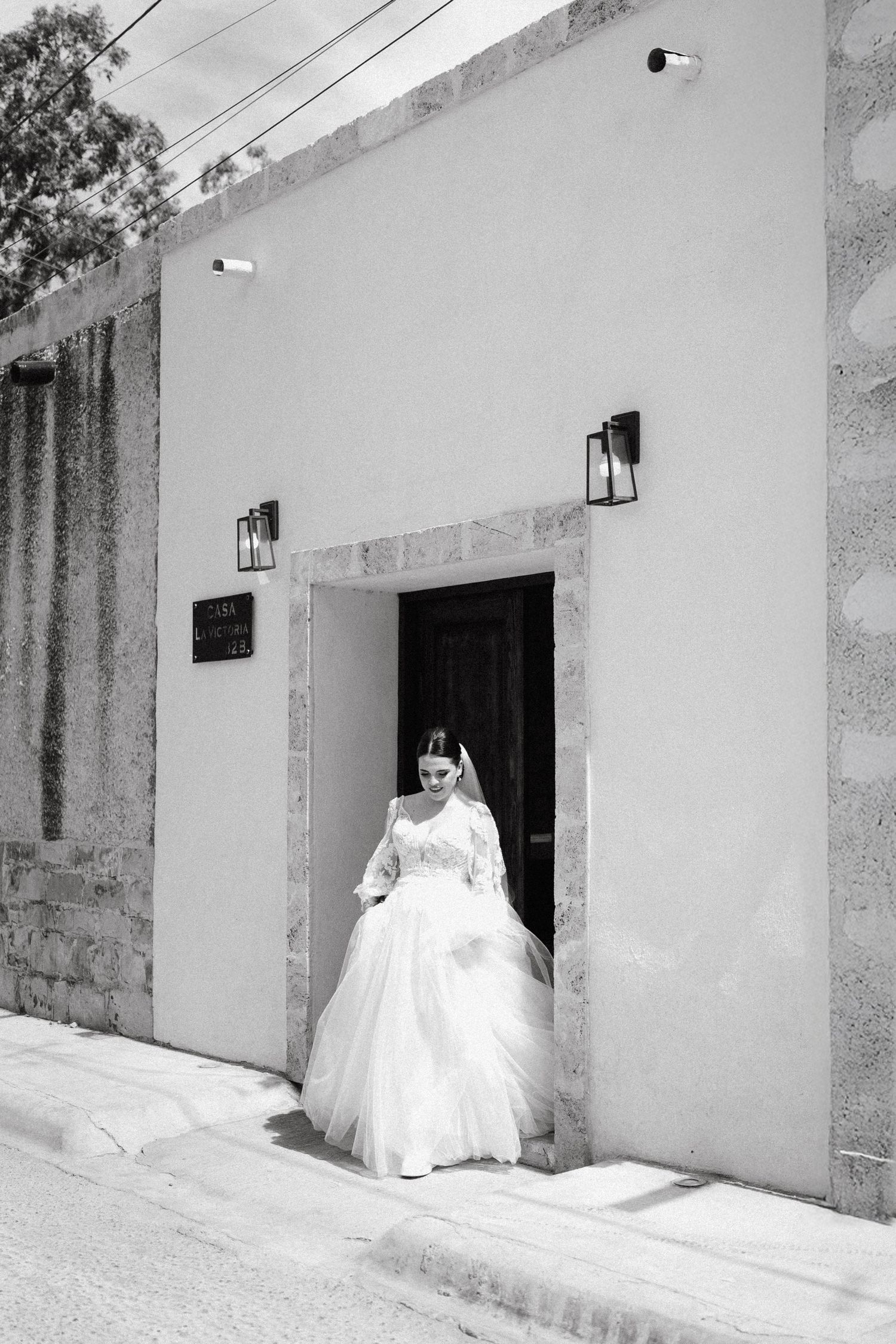 A white wedding dress photographed in sequence along a rustic stone wall with lanterns.