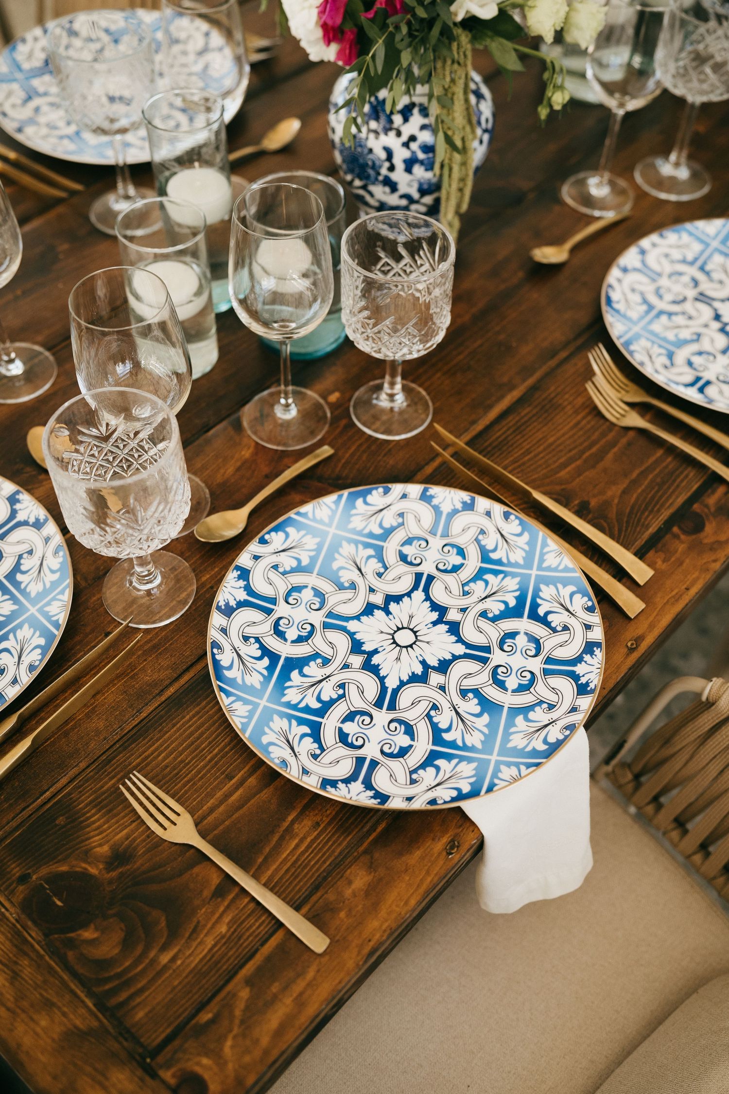 Elegant table setting with blue and white patterned plates on dark wooden table.