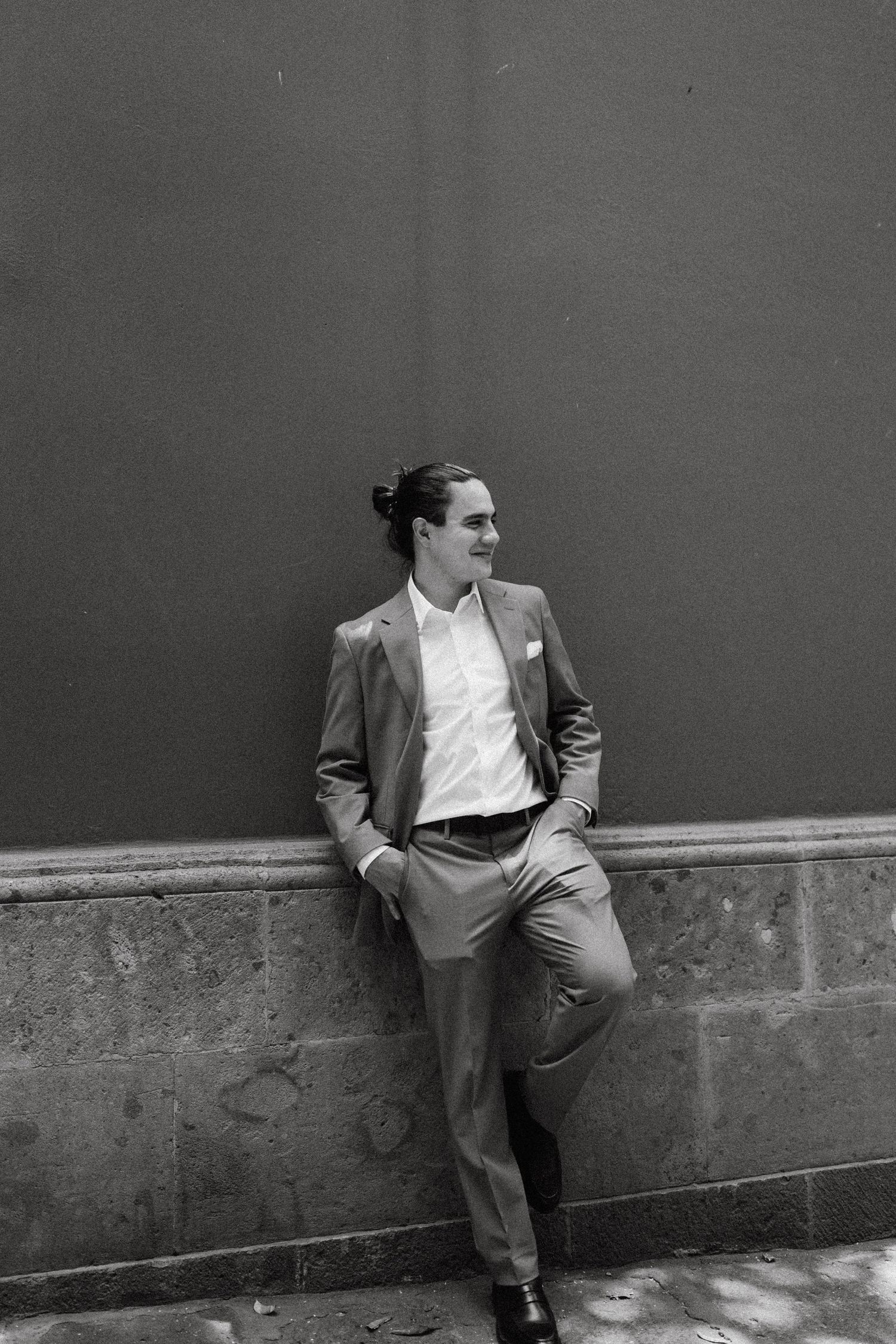 A series of black and white photos showing a person in a suit posing against a wall.