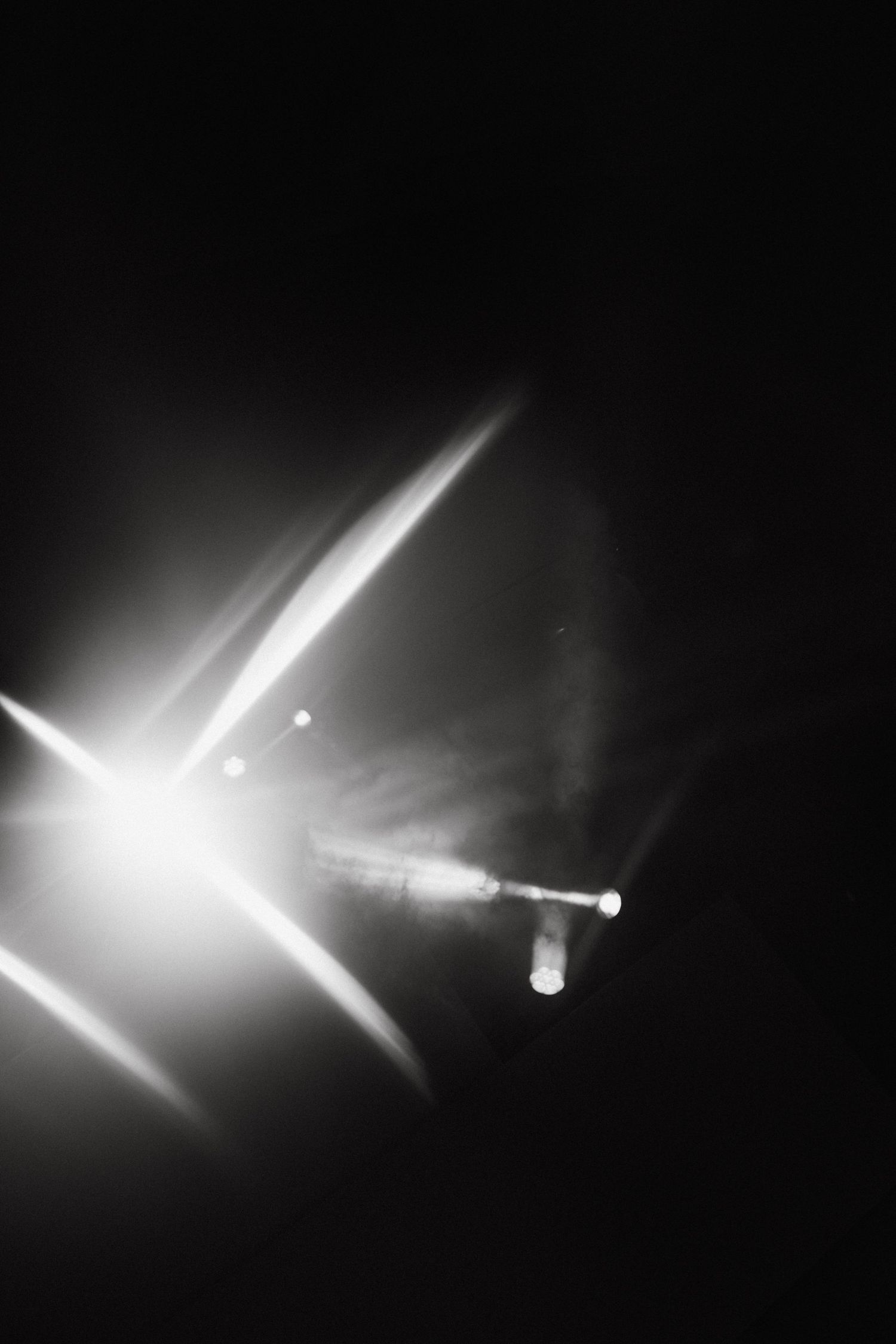 Abstract black and white photograph of bright stage lighting creating dramatic beams.