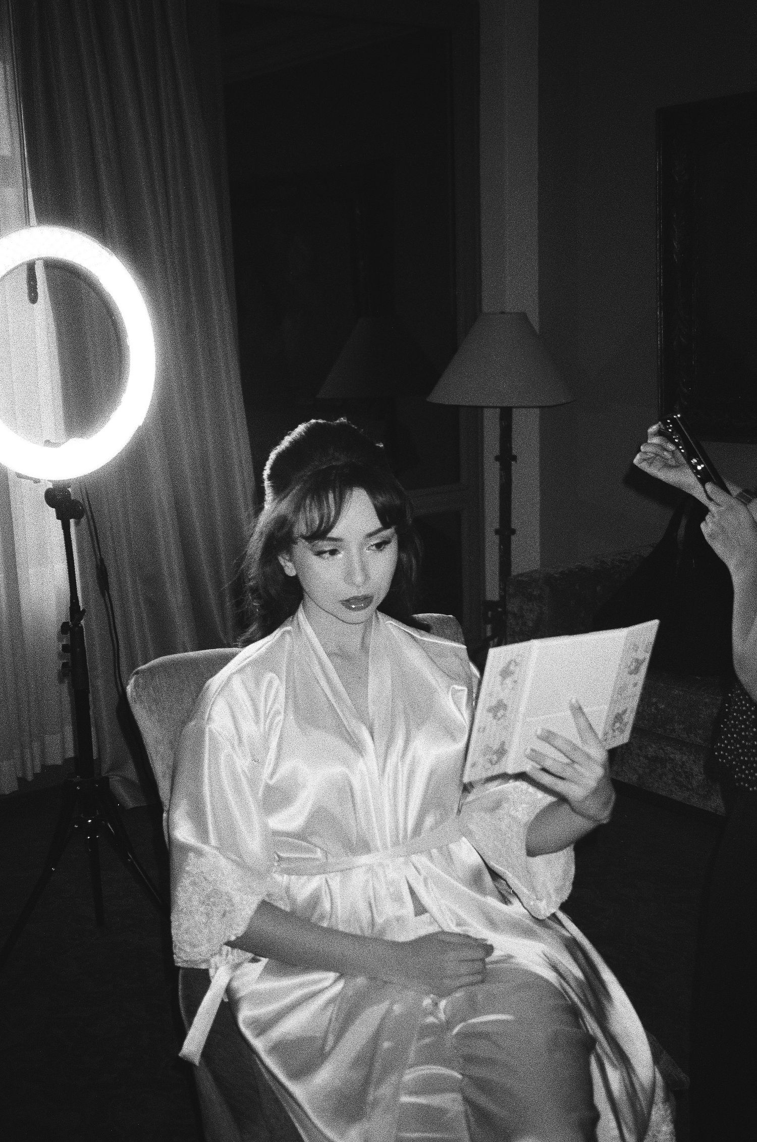 Getting ready scene with silk robe illuminated by ring light in dark room.