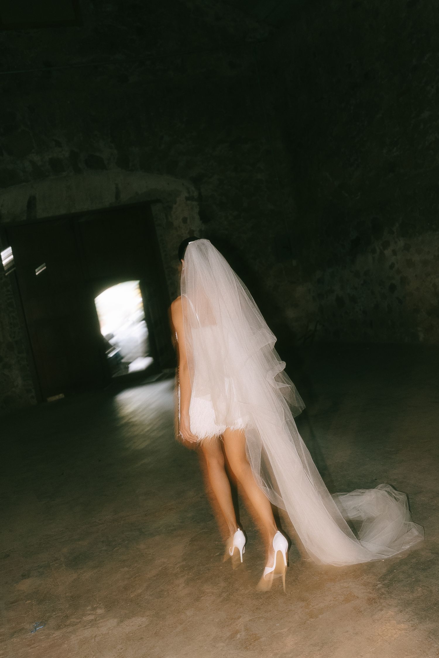 A close-up view of white wedding dress and heels in low light conditions.