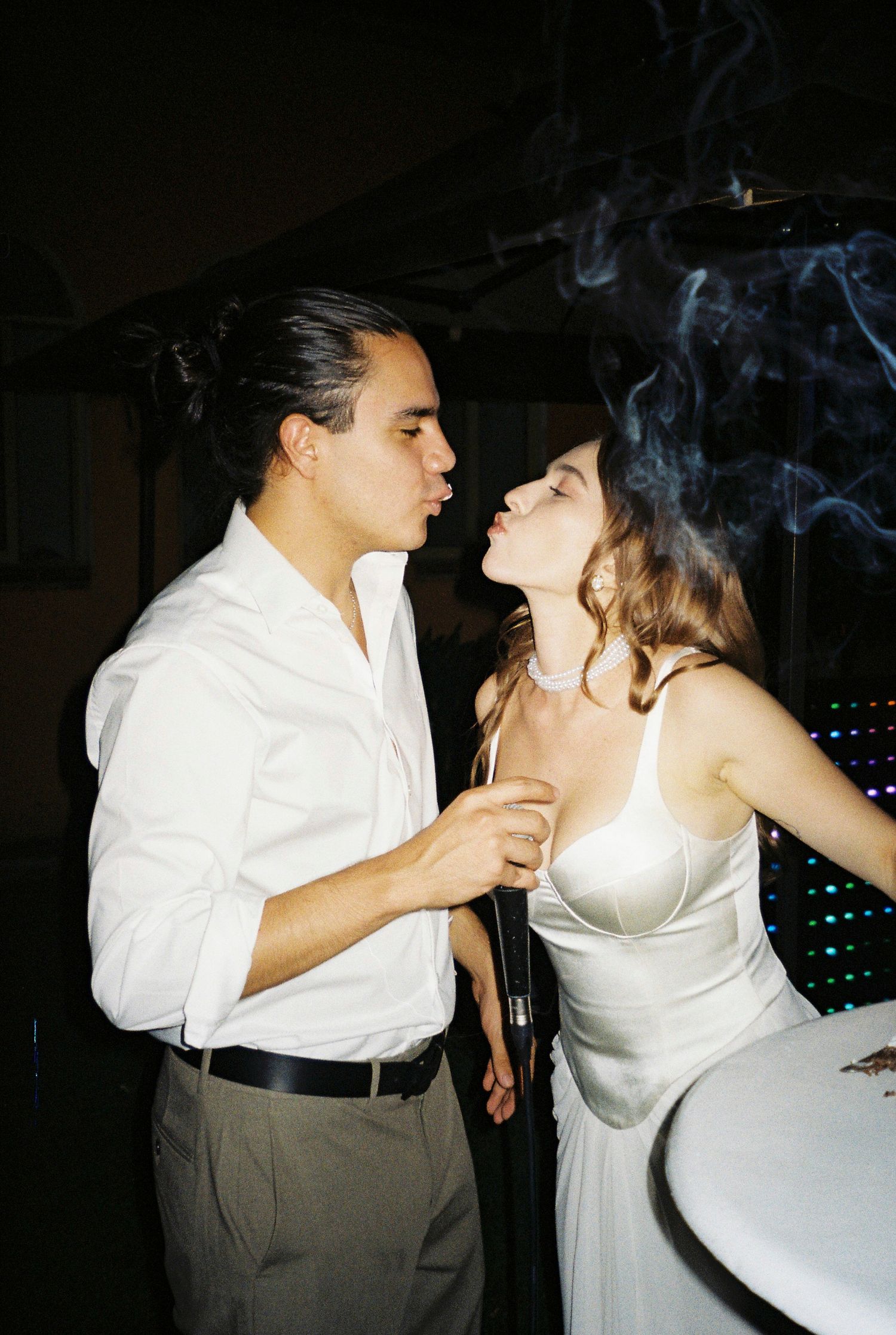 A romantic couple dancing together at a wedding reception, with the bride in white and groom in formal attire.