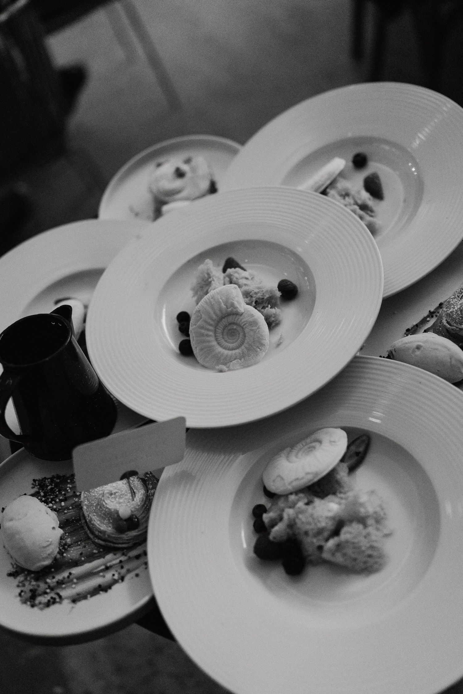 Black and white overhead view of plated meals at an elegant dinner service.
