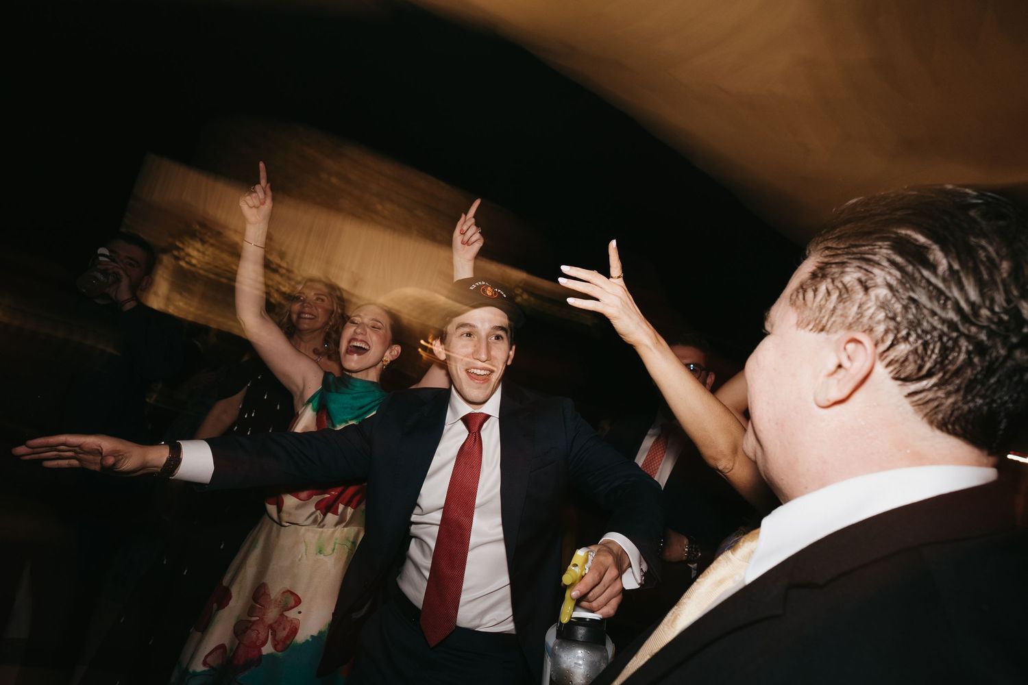 Energetic dance floor celebration at a wedding reception with guests dancing.
