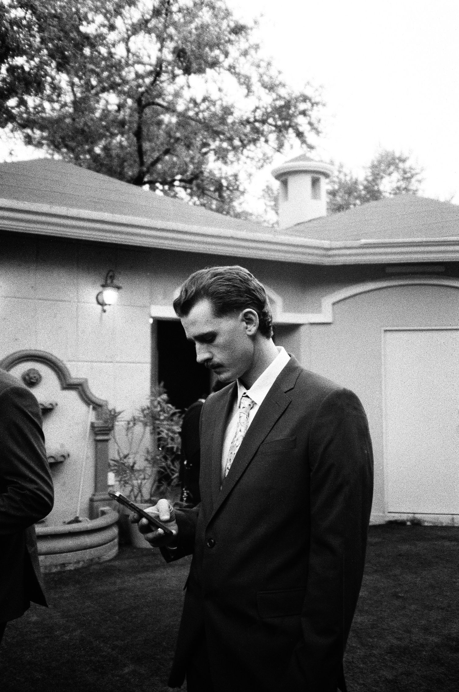Formal gathering in a backyard garden setting captured in black and white.