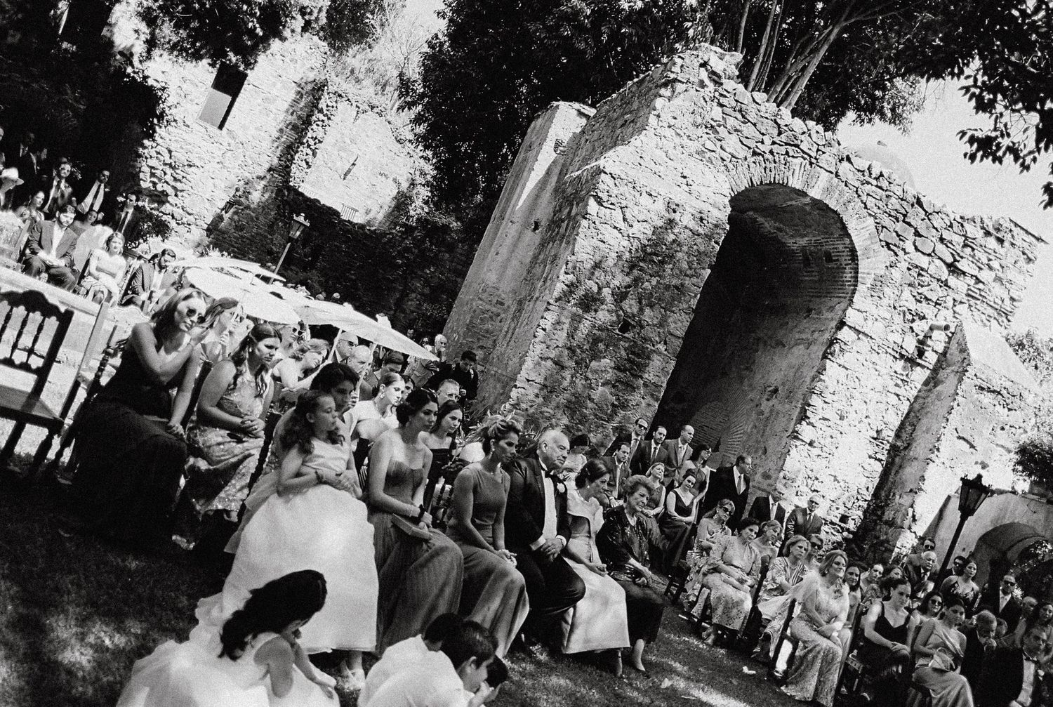 Black and white photos capture wedding guests mingling at an outdoor reception.